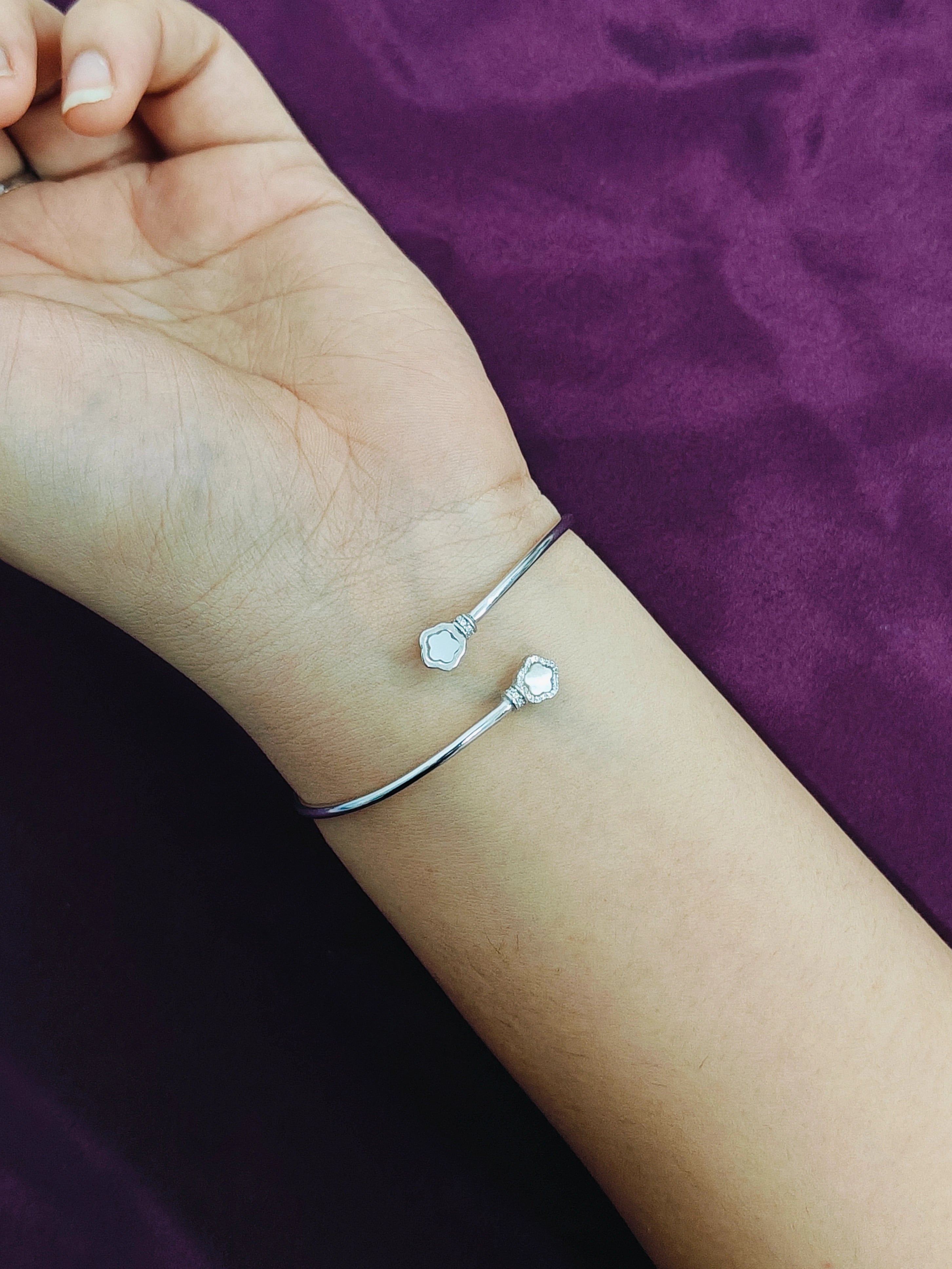 Silver bracelet on a wrist against a purple background