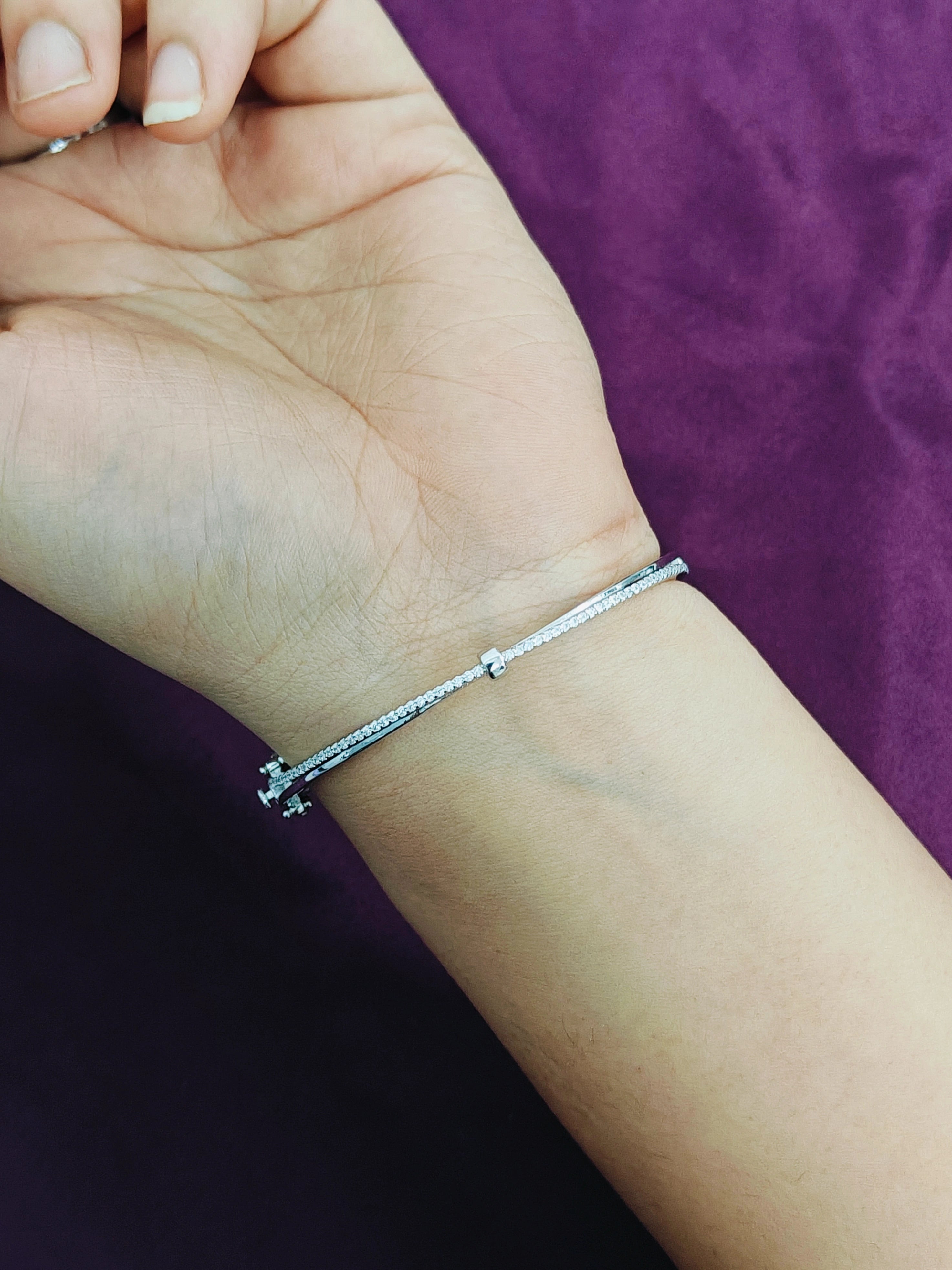 Silver bracelet on a wrist with a purple background