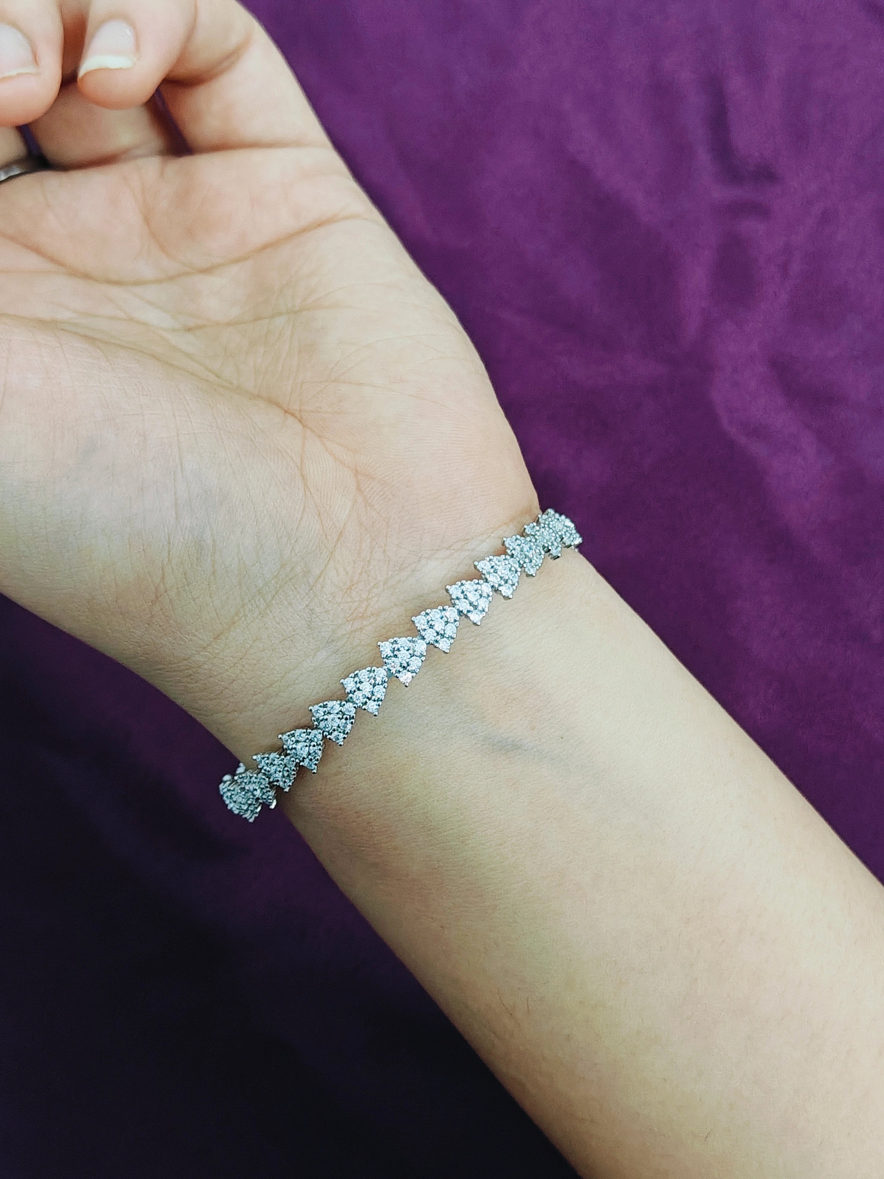 Silver bracelet on a person's wrist against a purple background