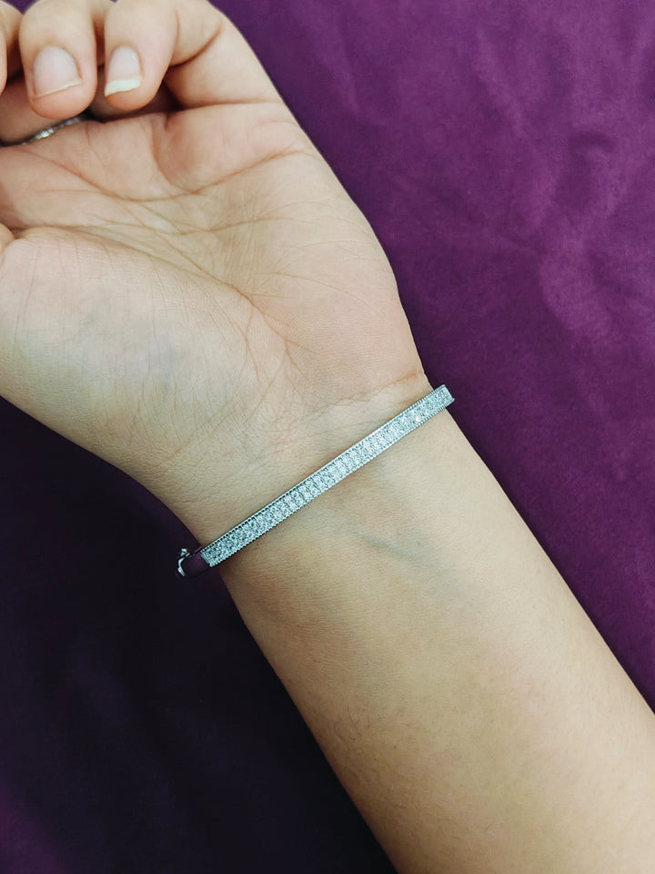Silver bracelet on a wrist with a purple background