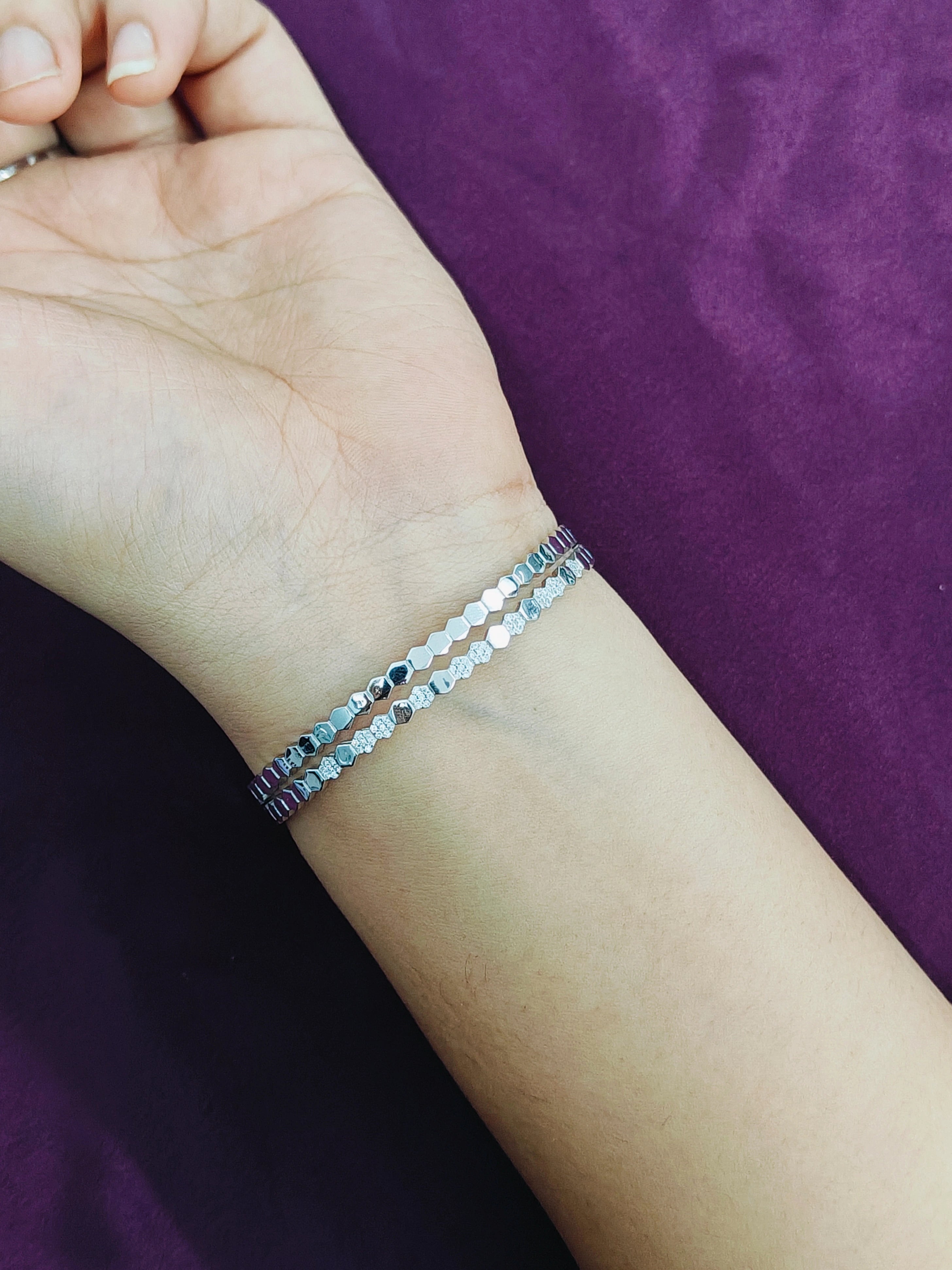 Silver bracelet on a wrist against a purple background