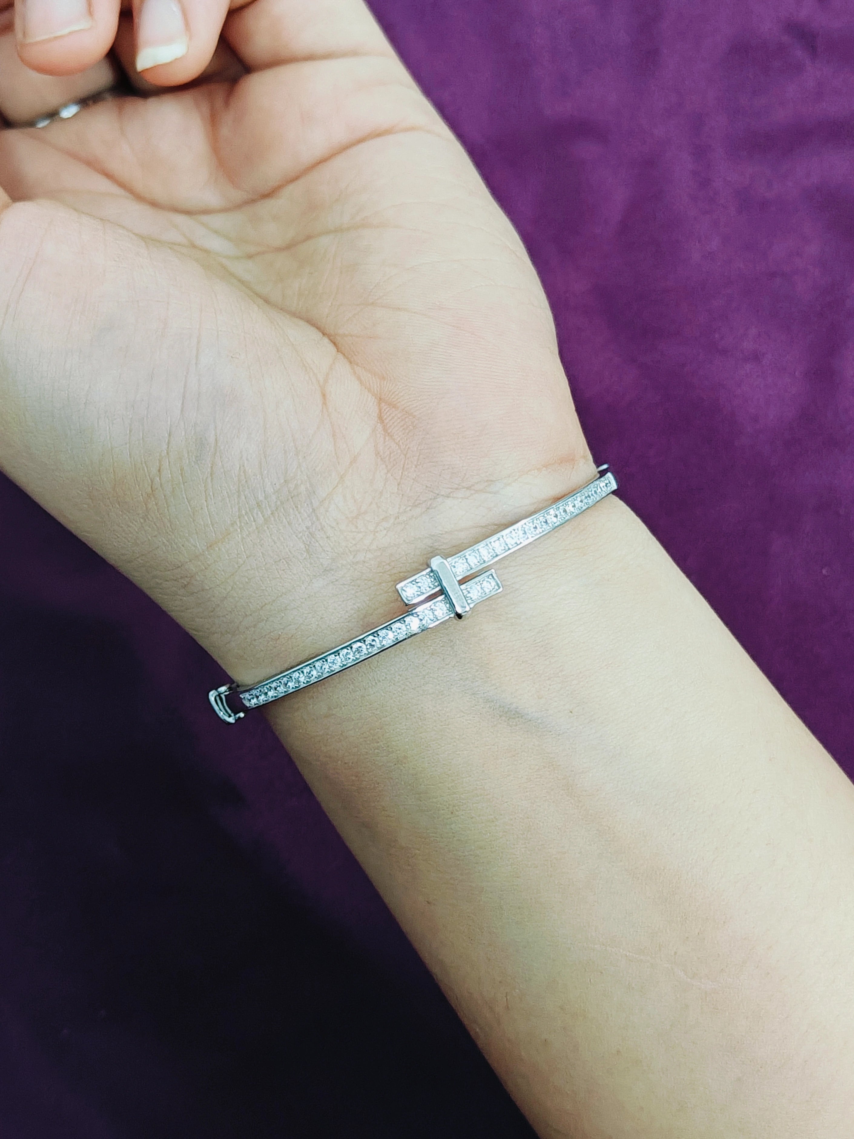 Silver bracelet on a wrist with a purple background
