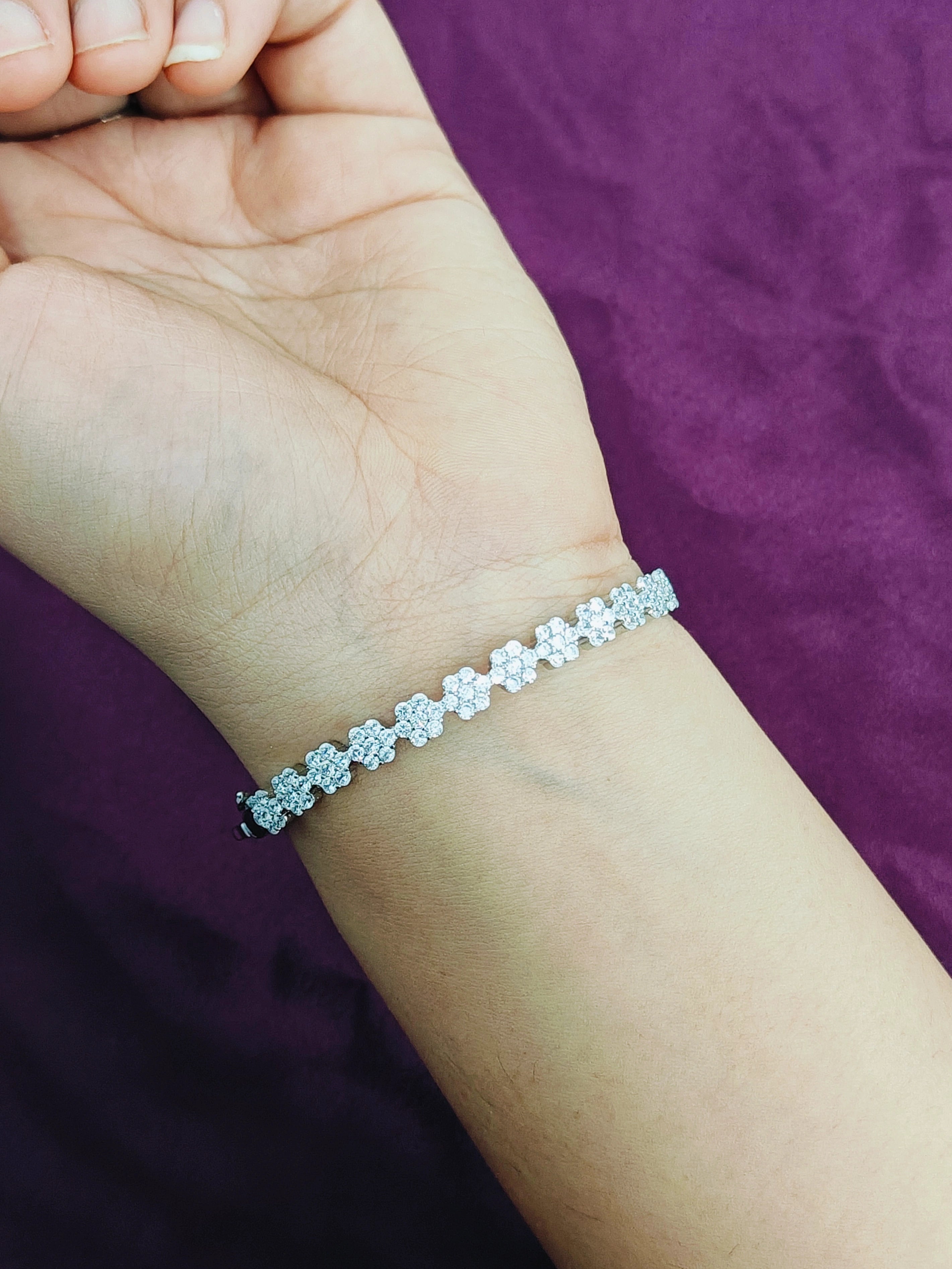 Silver bracelet on a wrist with a purple background