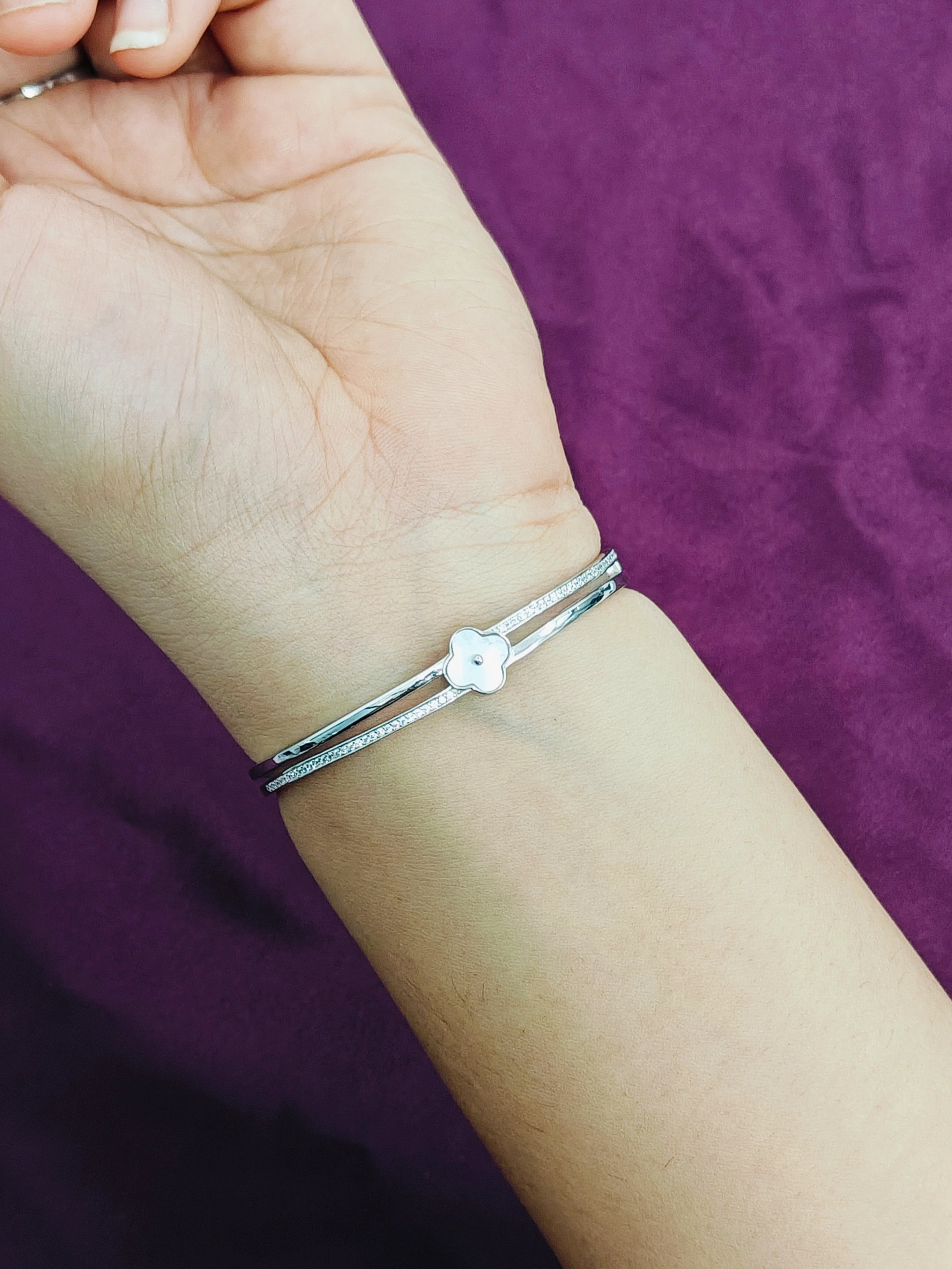 Silver bracelet on a wrist with a purple background