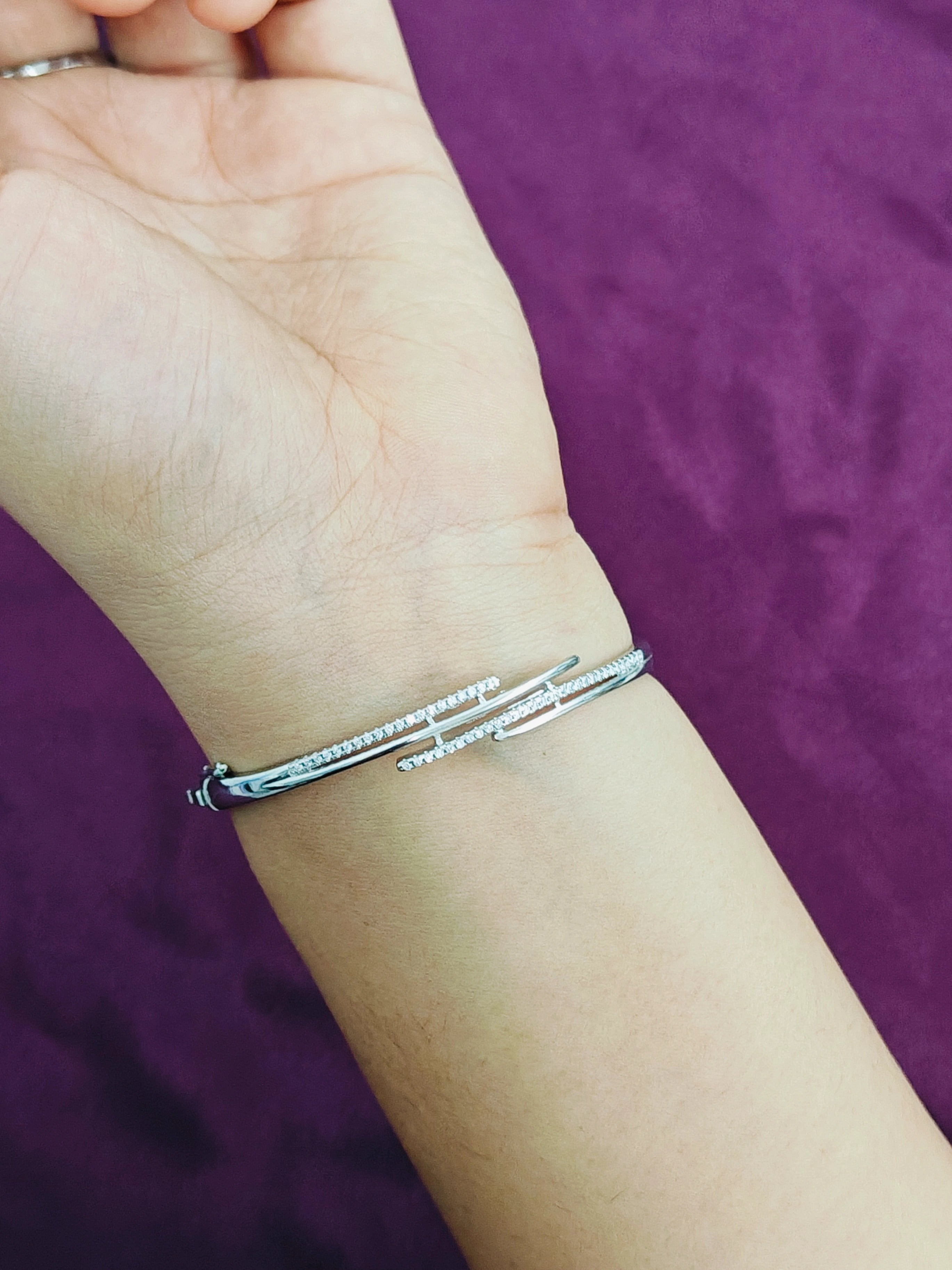 Silver bracelet on a wrist against a purple background