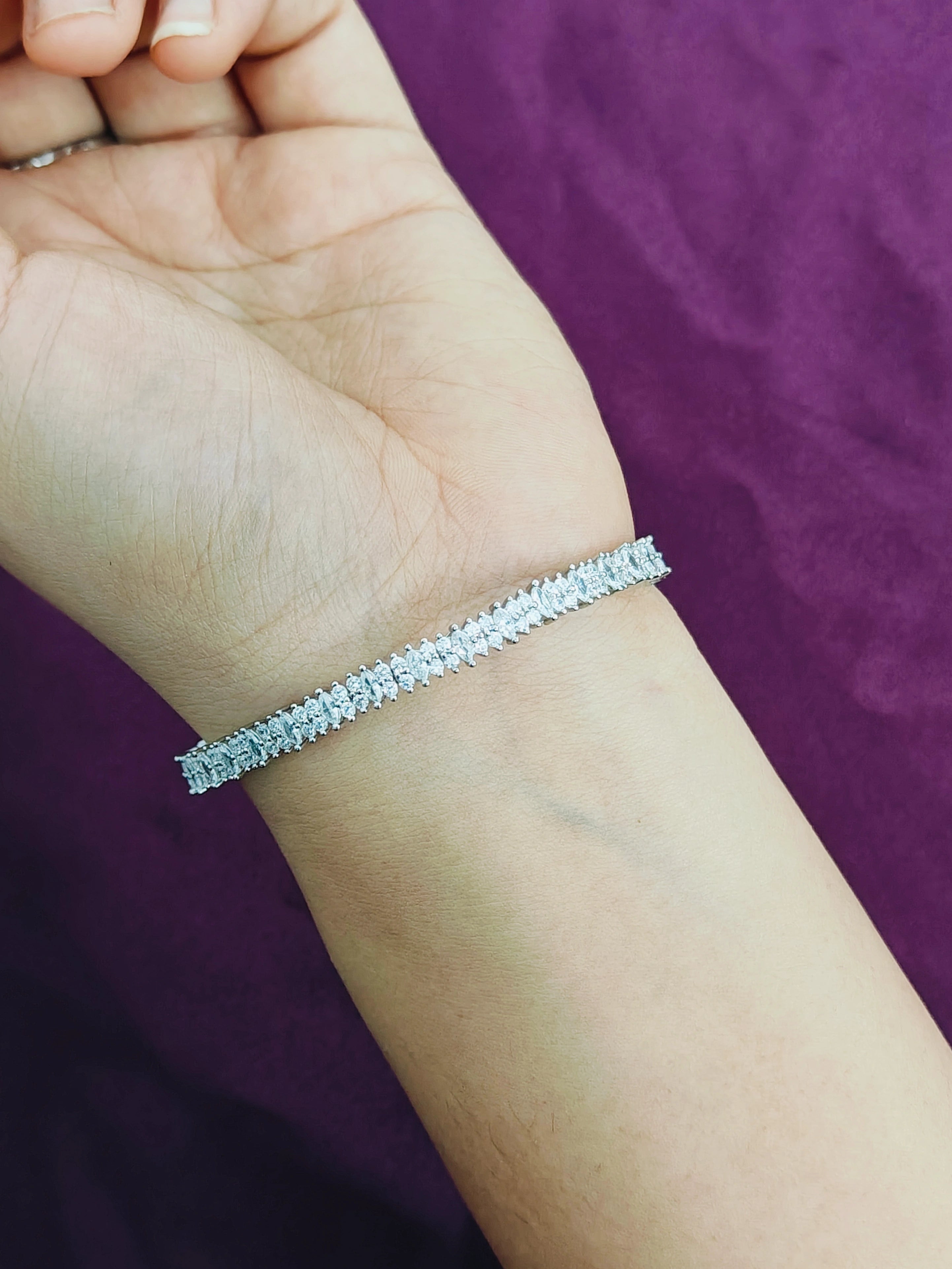 Silver bracelet on a wrist with a purple background