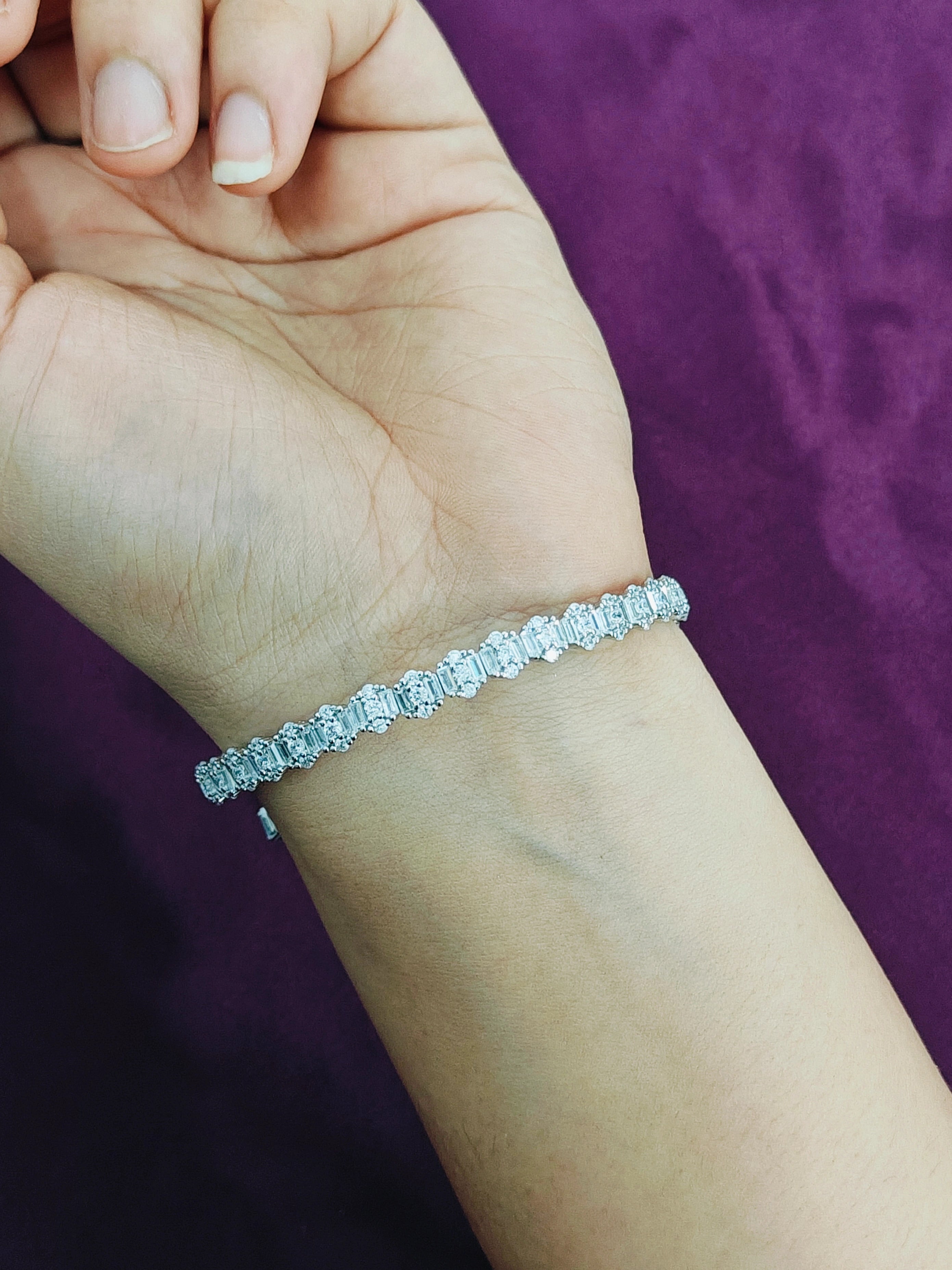 Silver bracelet on a wrist with a purple background