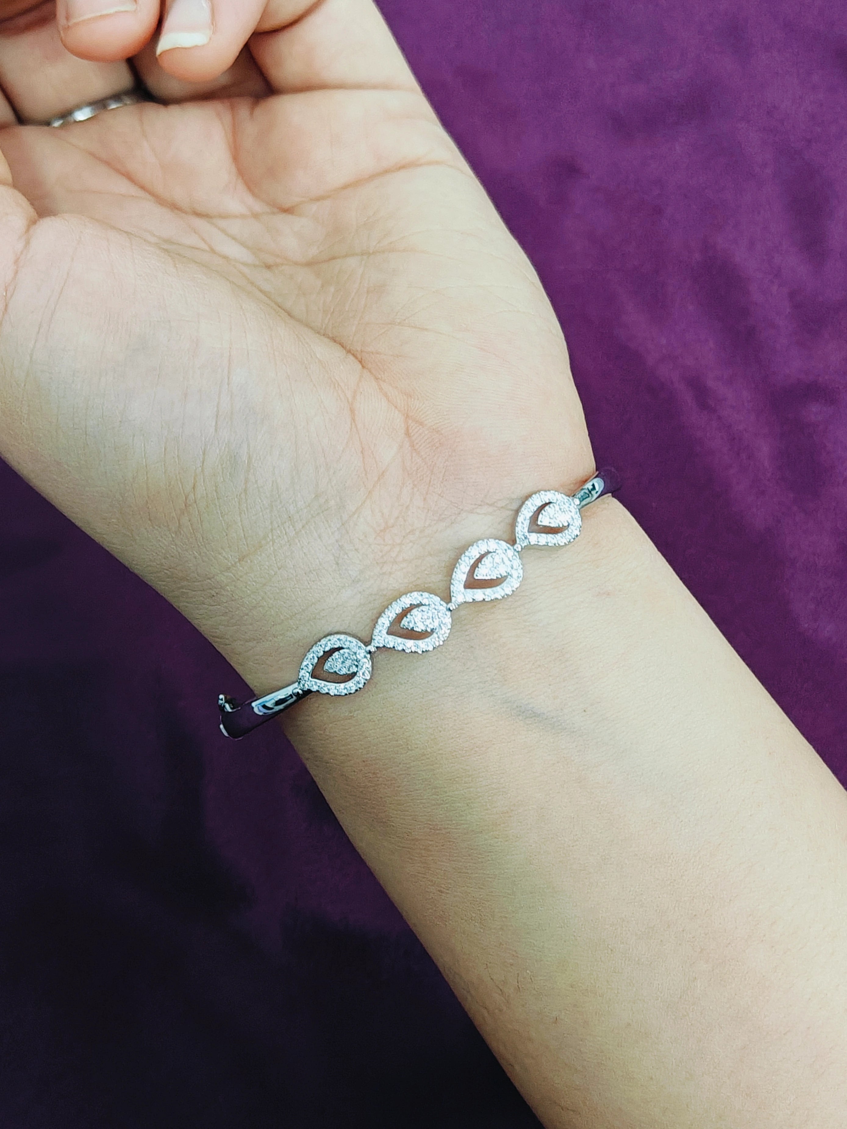 Silver bracelet on a person's wrist with a purple background