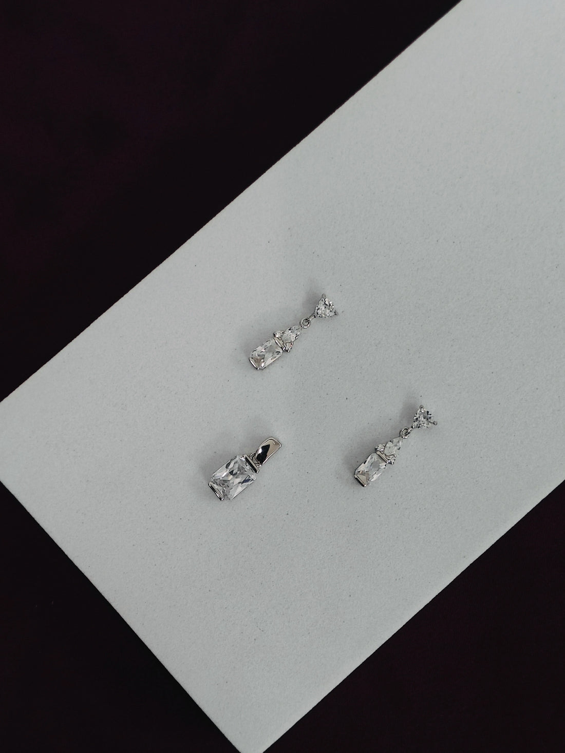Set of silver earrings on a gray surface with black background