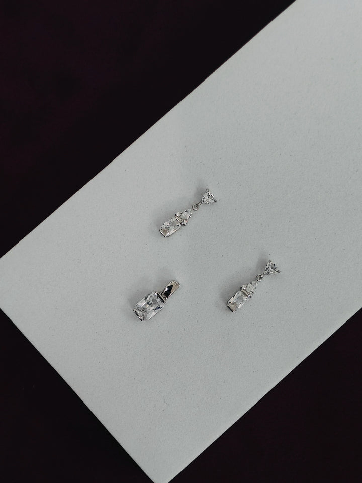 Set of silver earrings on a gray surface with black background