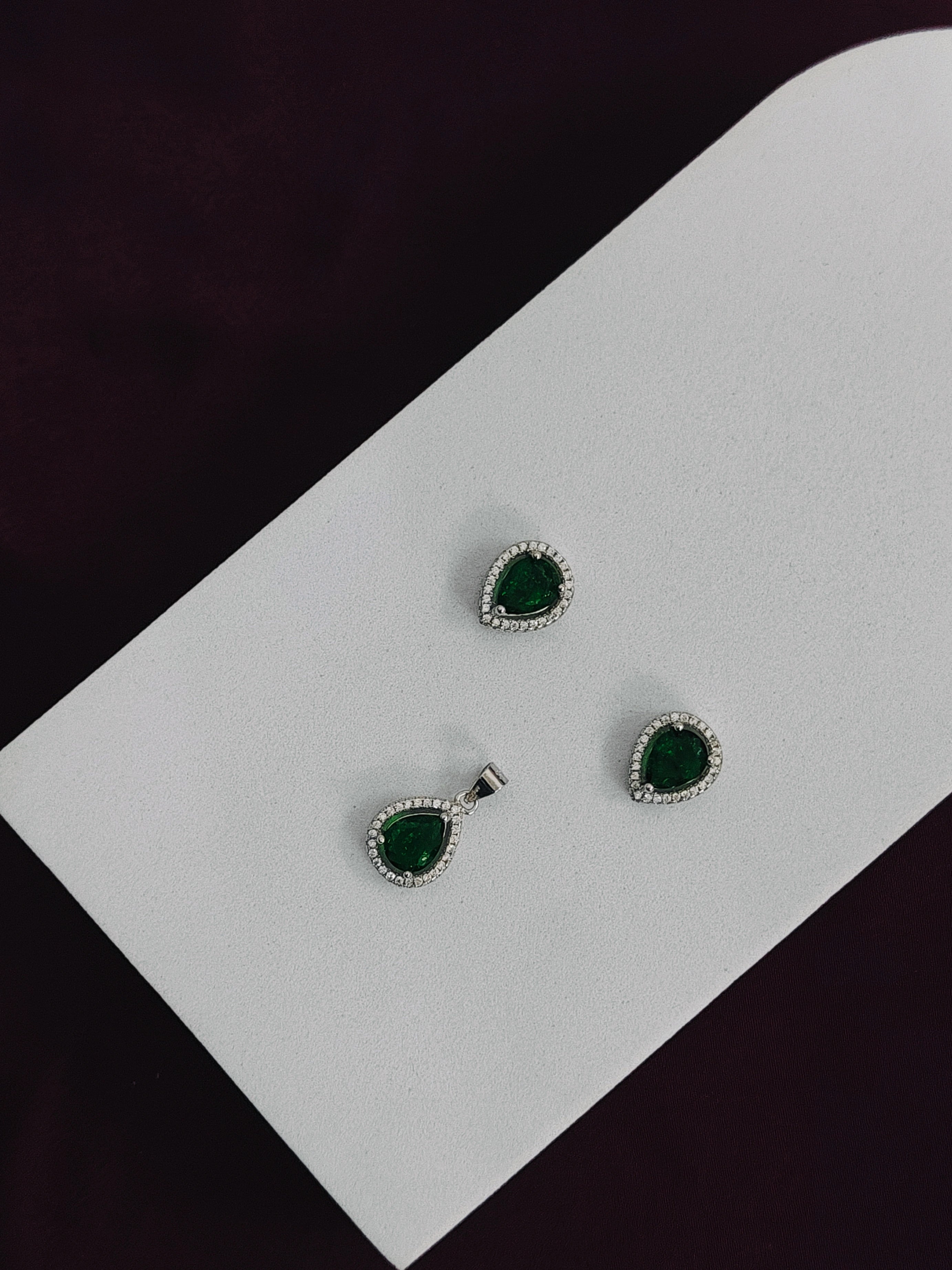 Set of green gemstone earrings on a white card with a black background