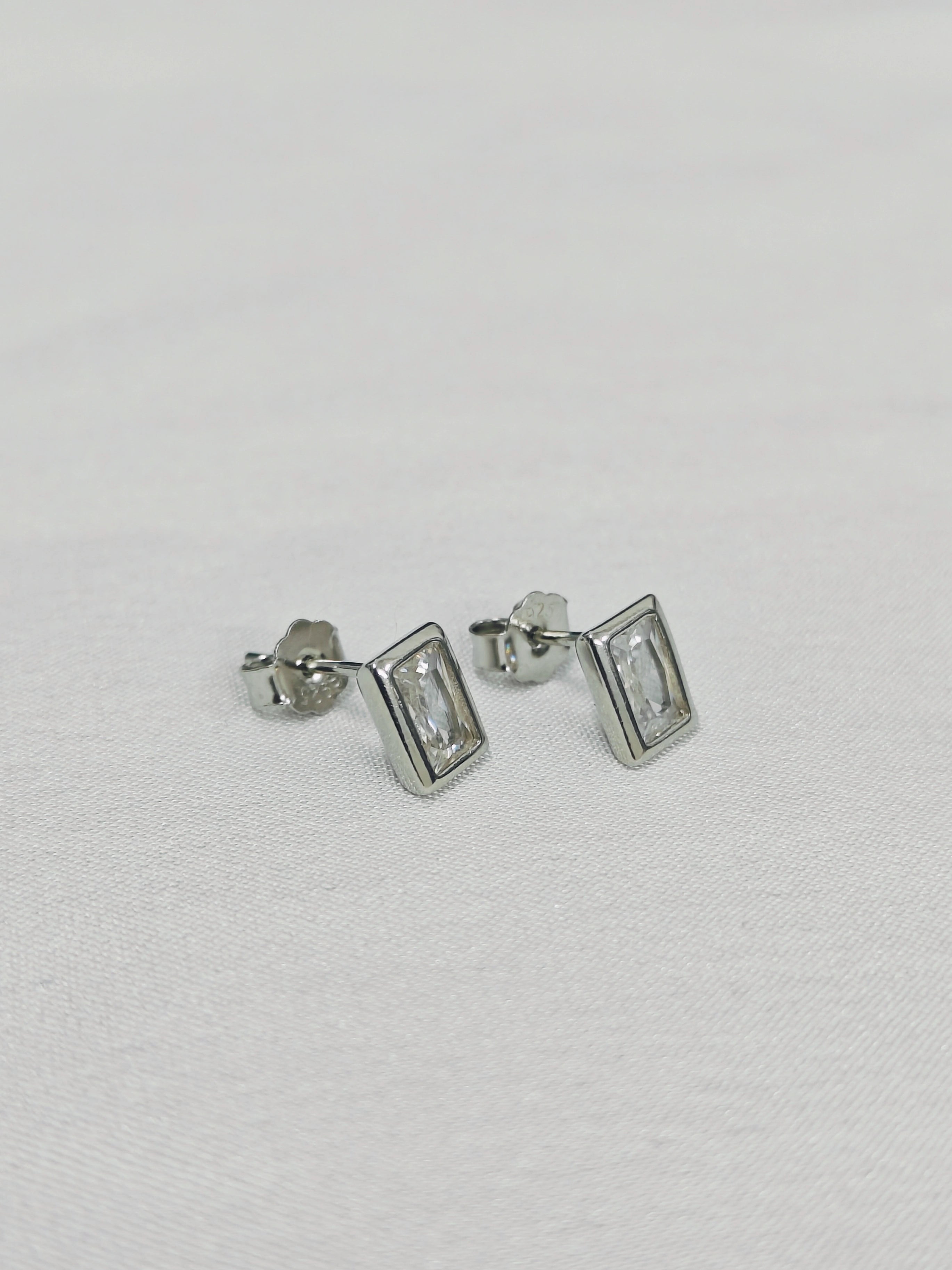 Pair of silver rectangular stud earrings on a light gray background
