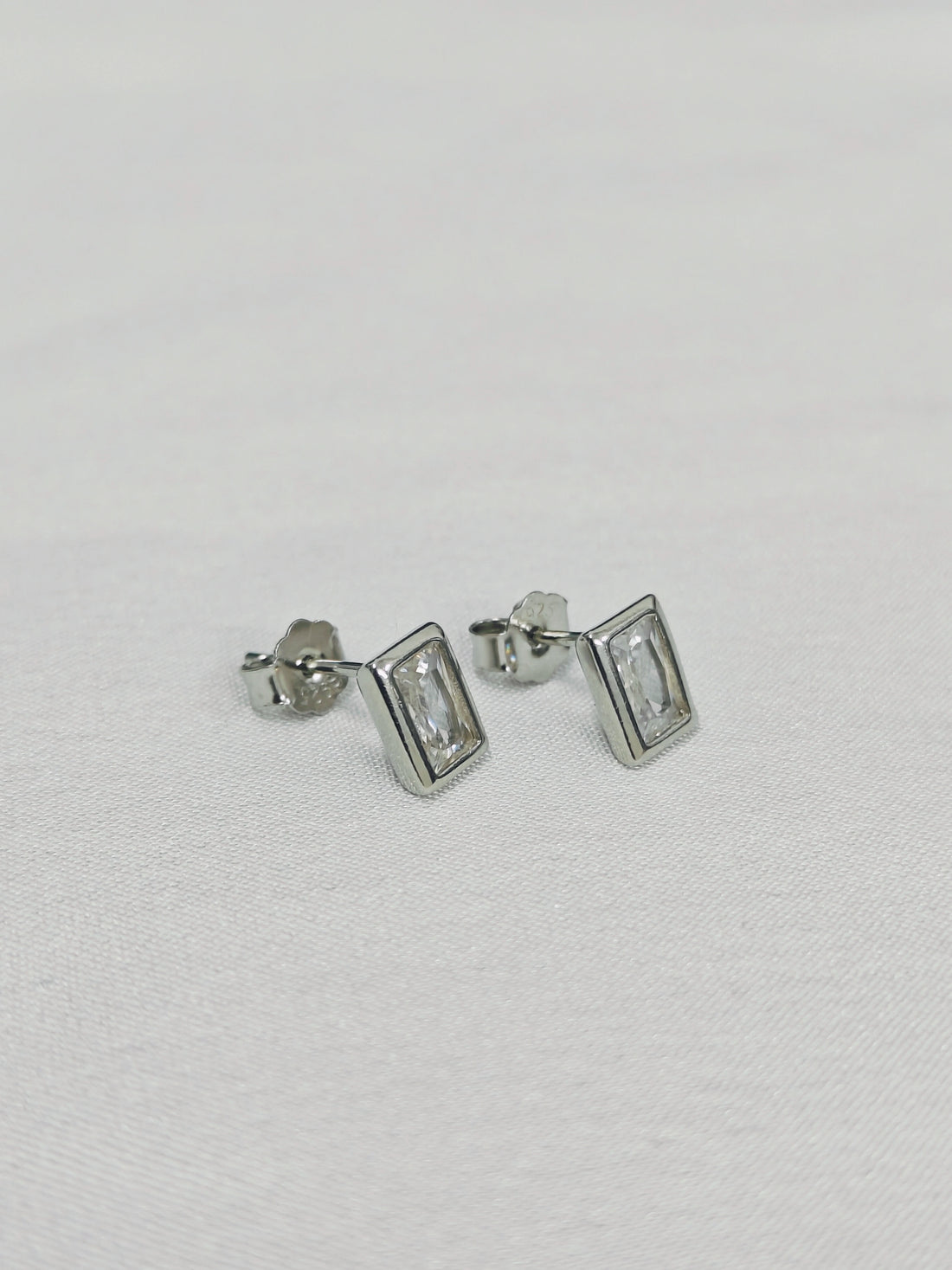 Pair of silver rectangular stud earrings on a light gray background