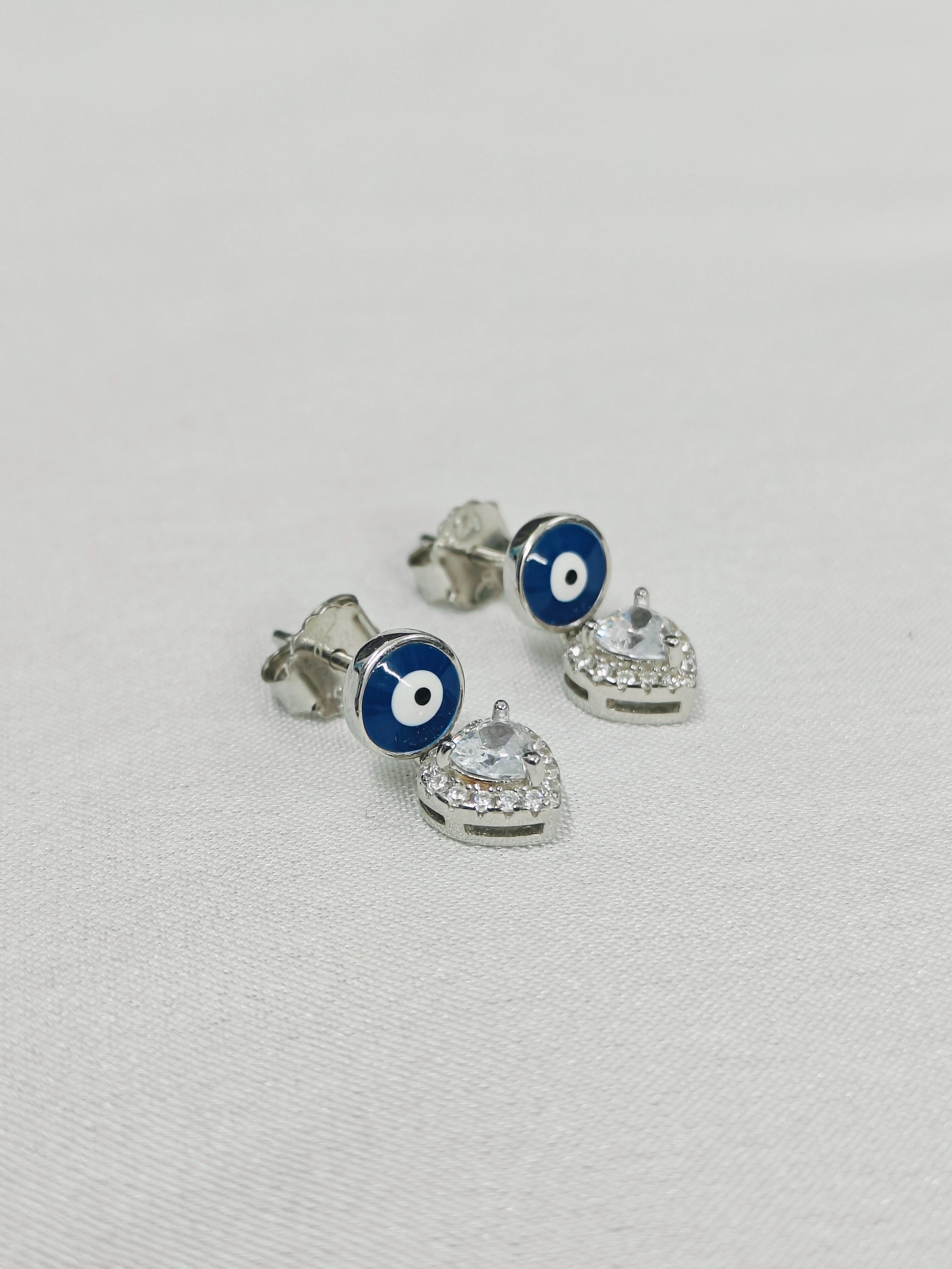 Silver earrings with blue and white circular designs on a light gray background