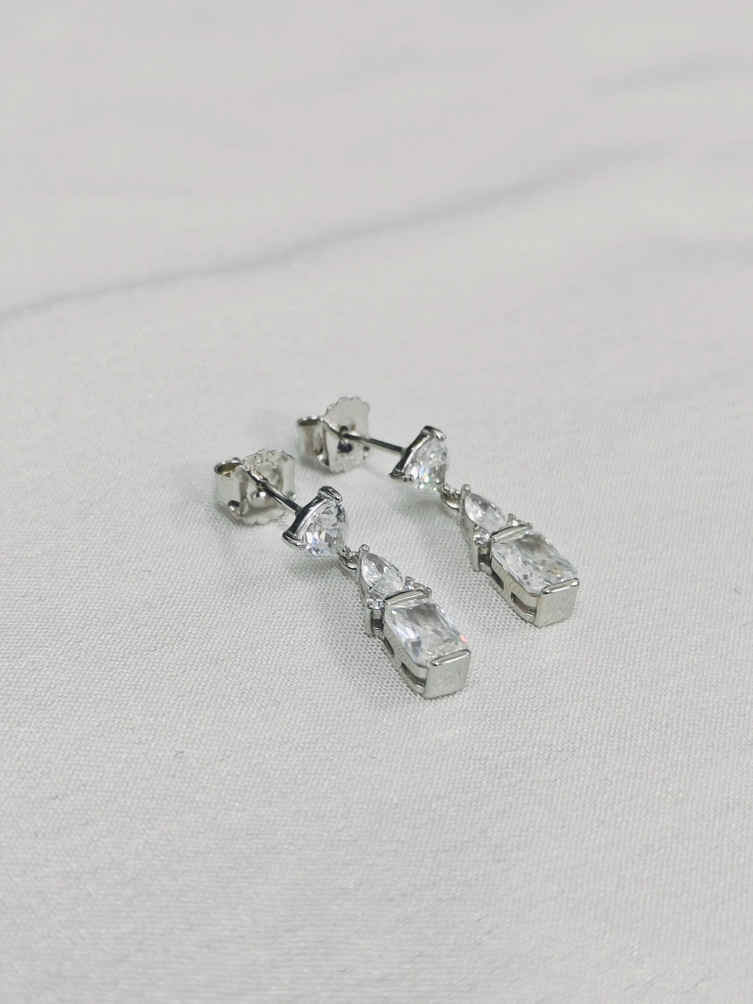 Silver earrings with clear gemstones on a light gray background