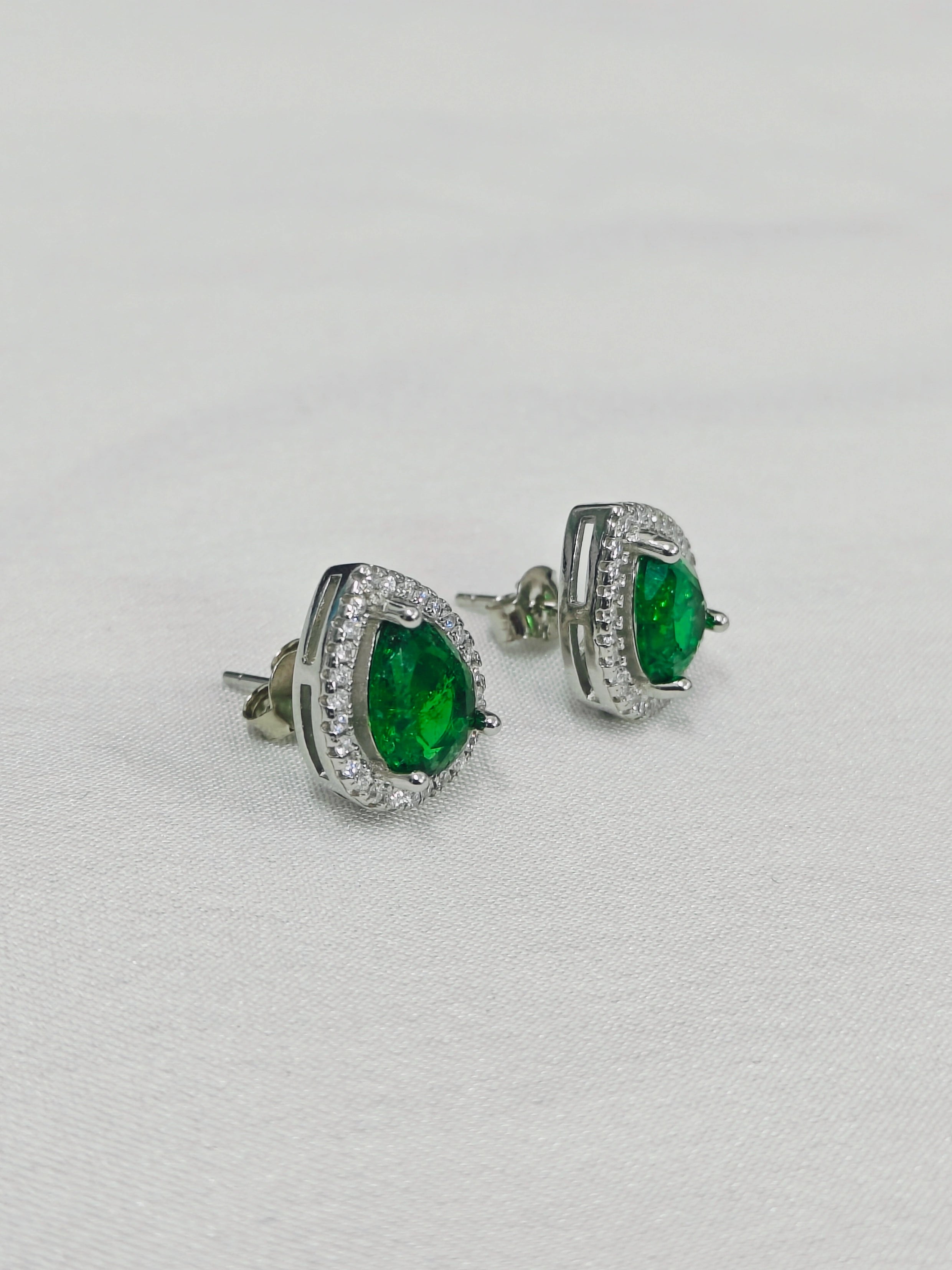 Pair of emerald green gemstone earrings on a light gray background