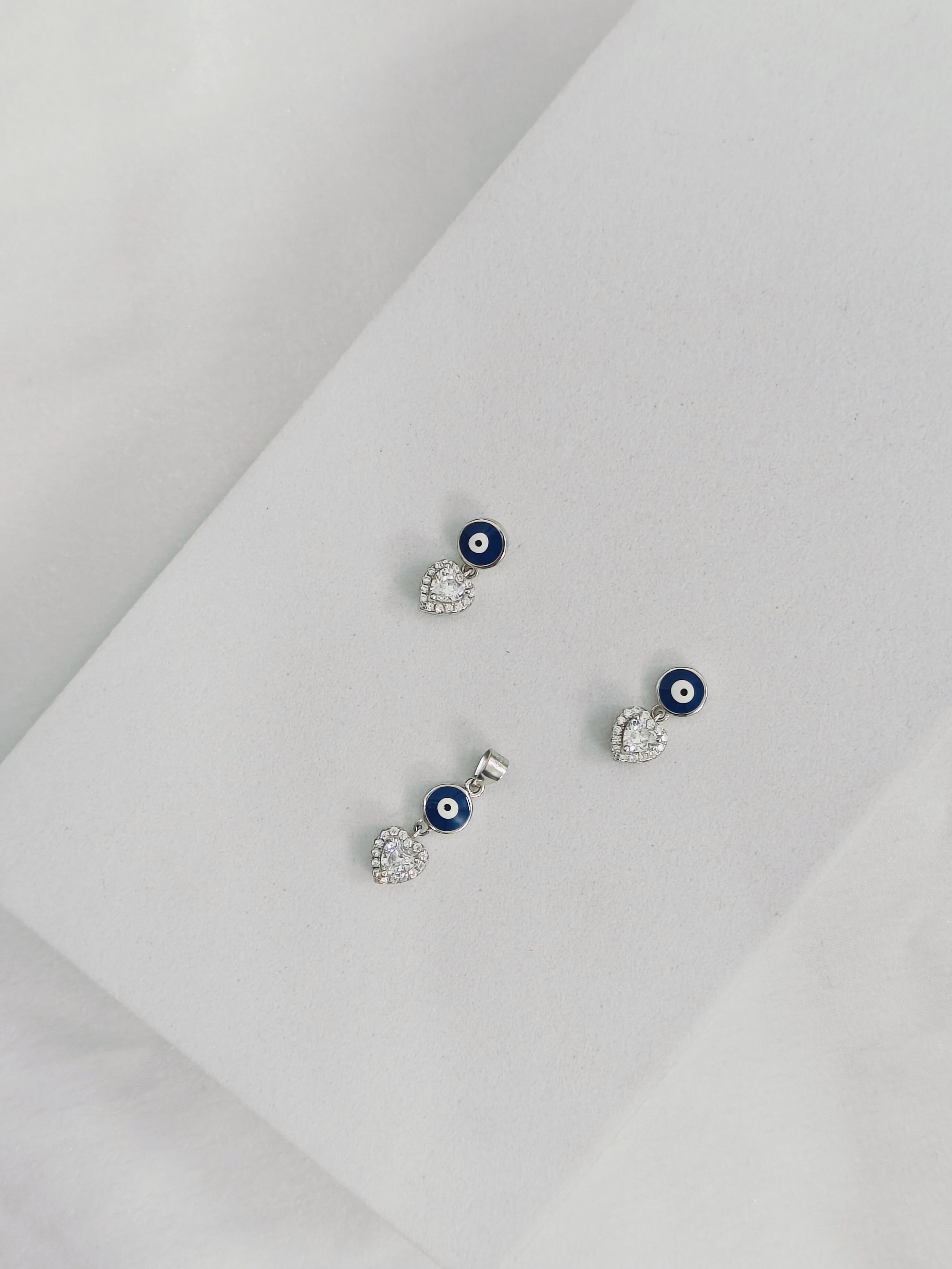 Set of silver earrings with blue eye design on a light gray background