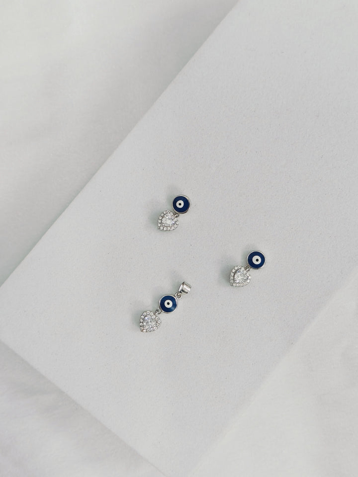 Set of silver earrings with blue eye design on a light gray background