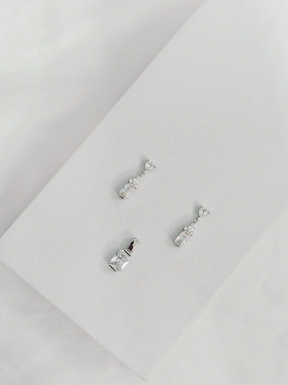 Pair of silver earrings on a light gray surface