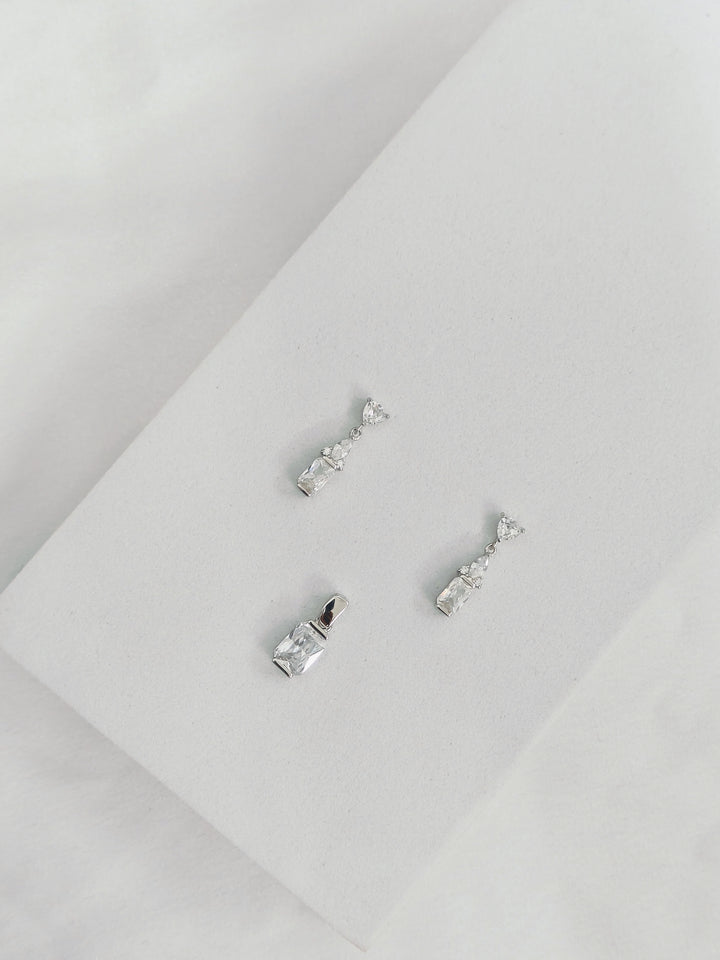 Pair of silver earrings on a light gray surface