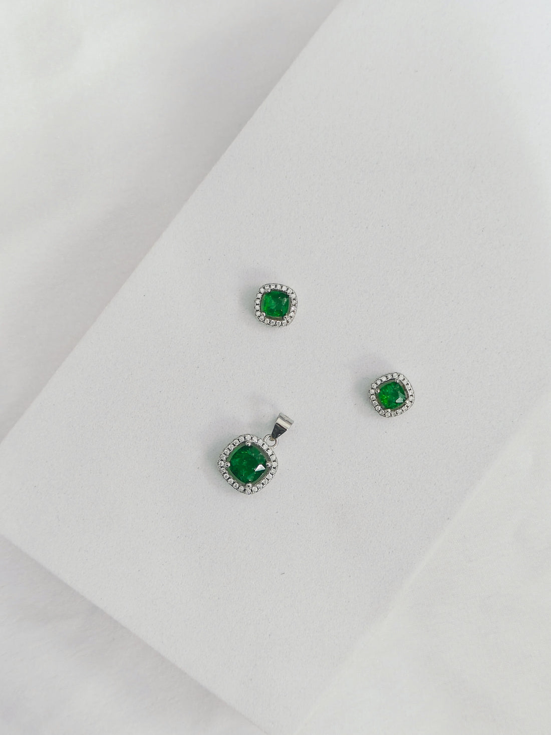 Green gemstone earrings on a light gray background