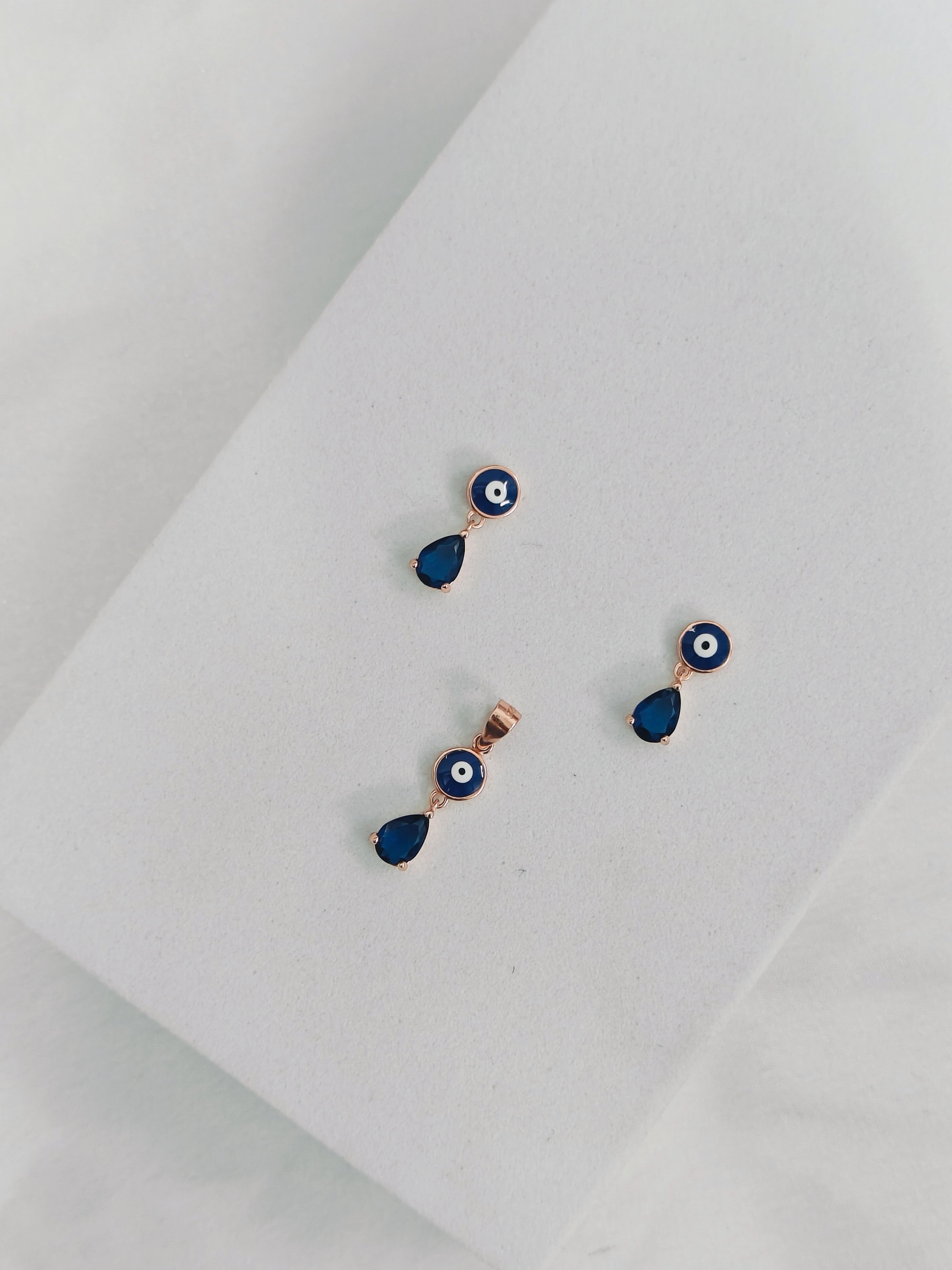 Pair of blue teardrop earrings with gold accents on a light gray background