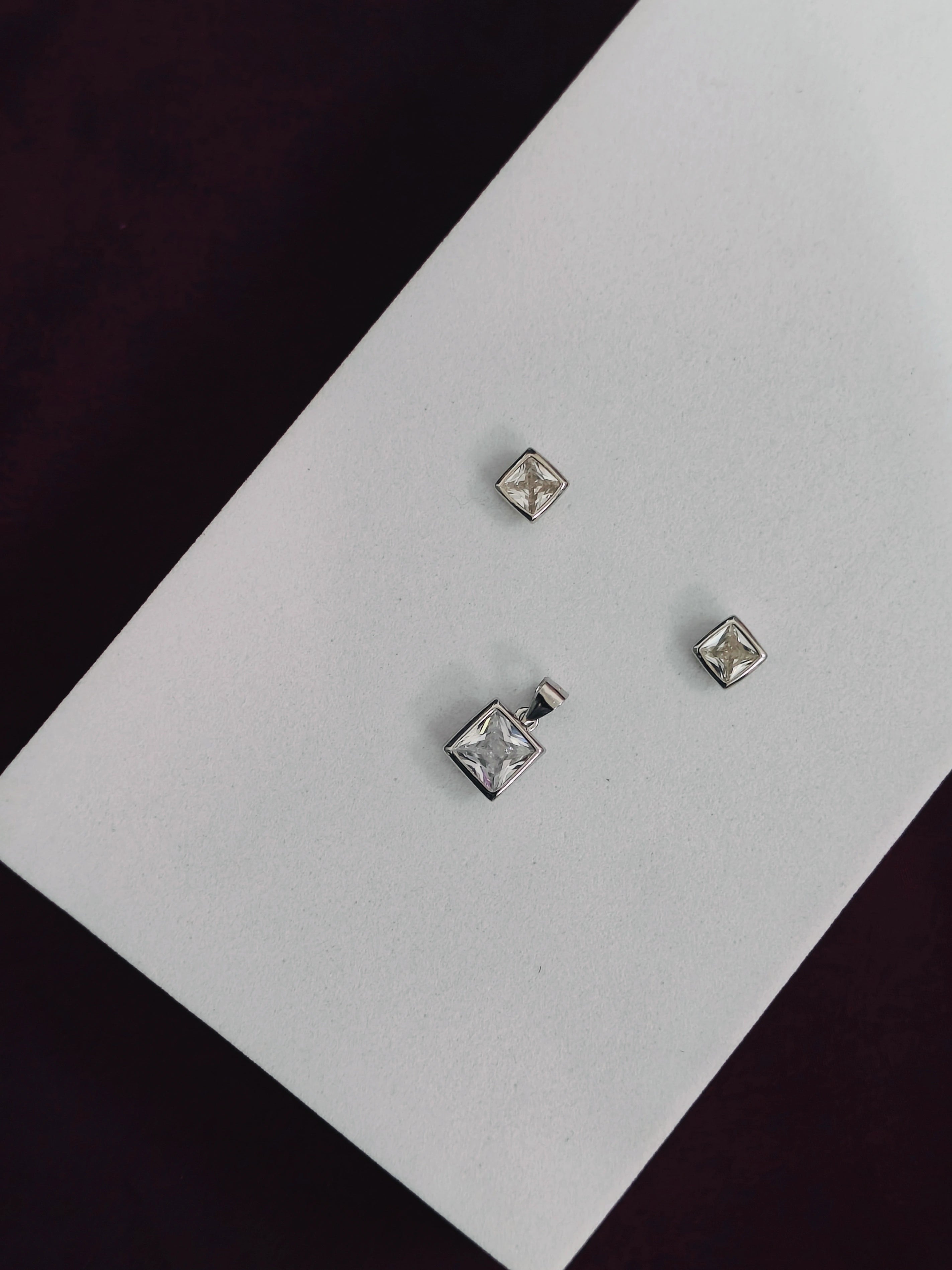 Silver square stud earrings on a white card with a black background