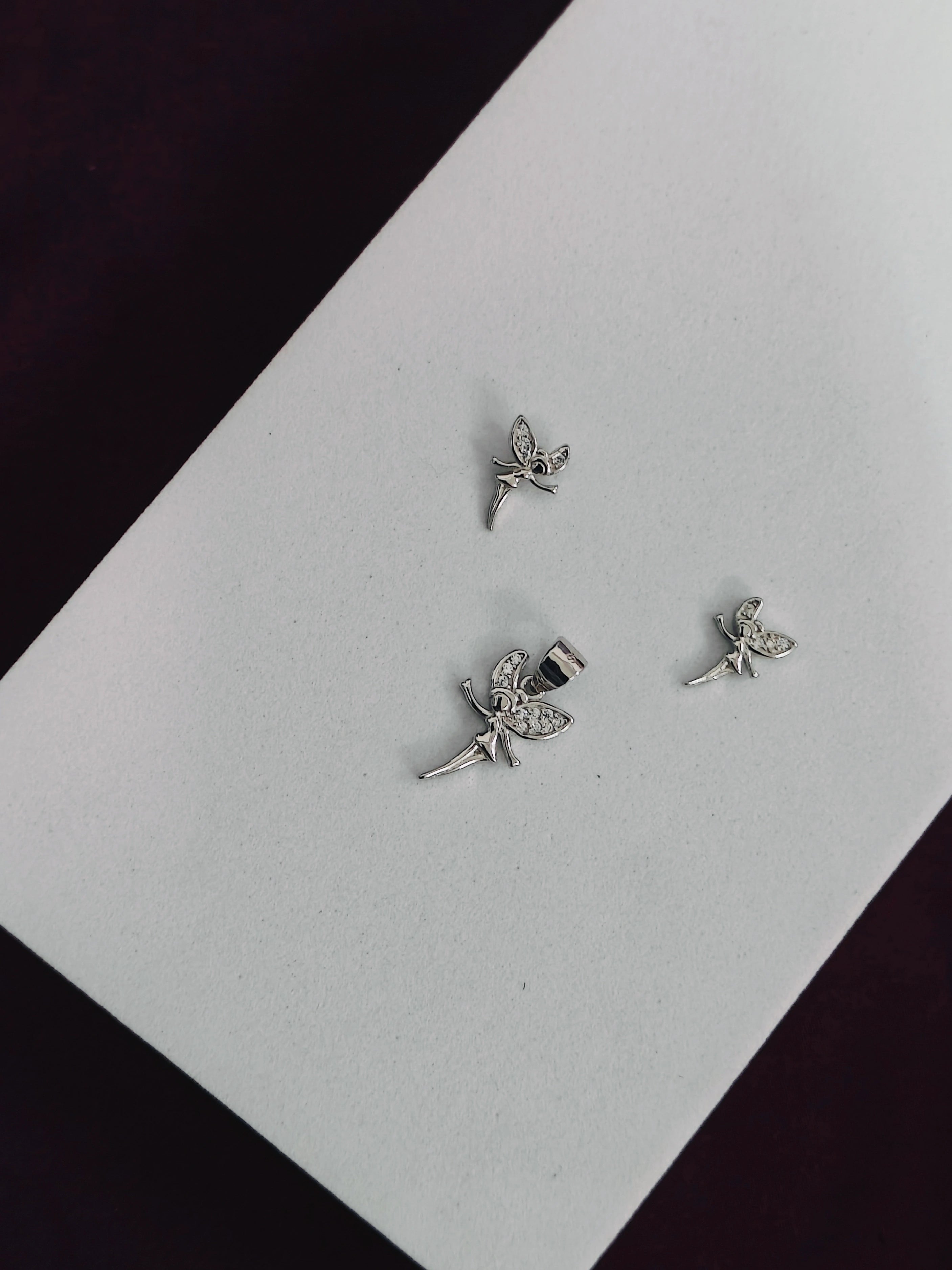 Silver fairy earrings on a white card with a black background