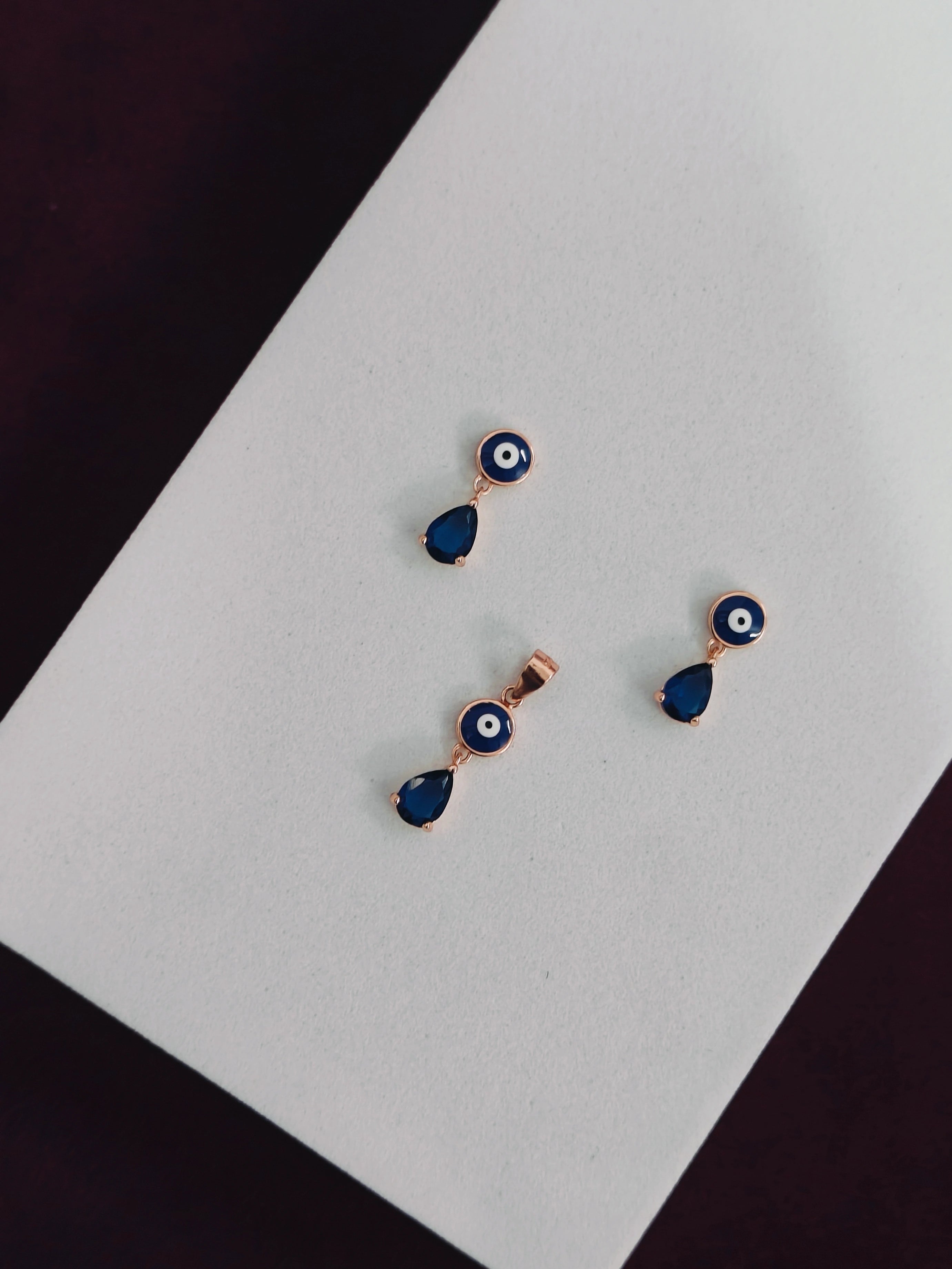 Pair of earrings with blue teardrop designs on a white card