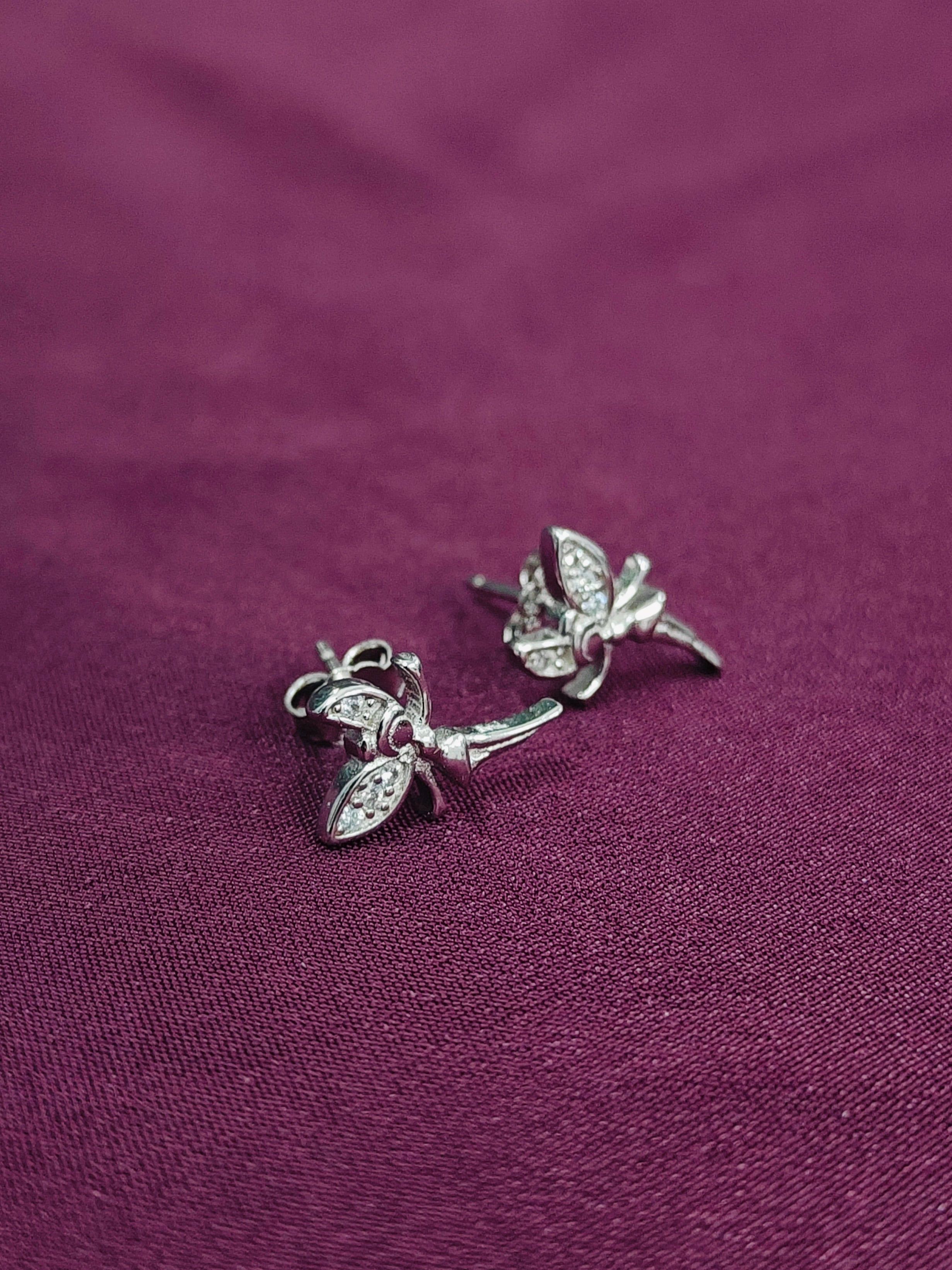 Silver earrings on a purple fabric background