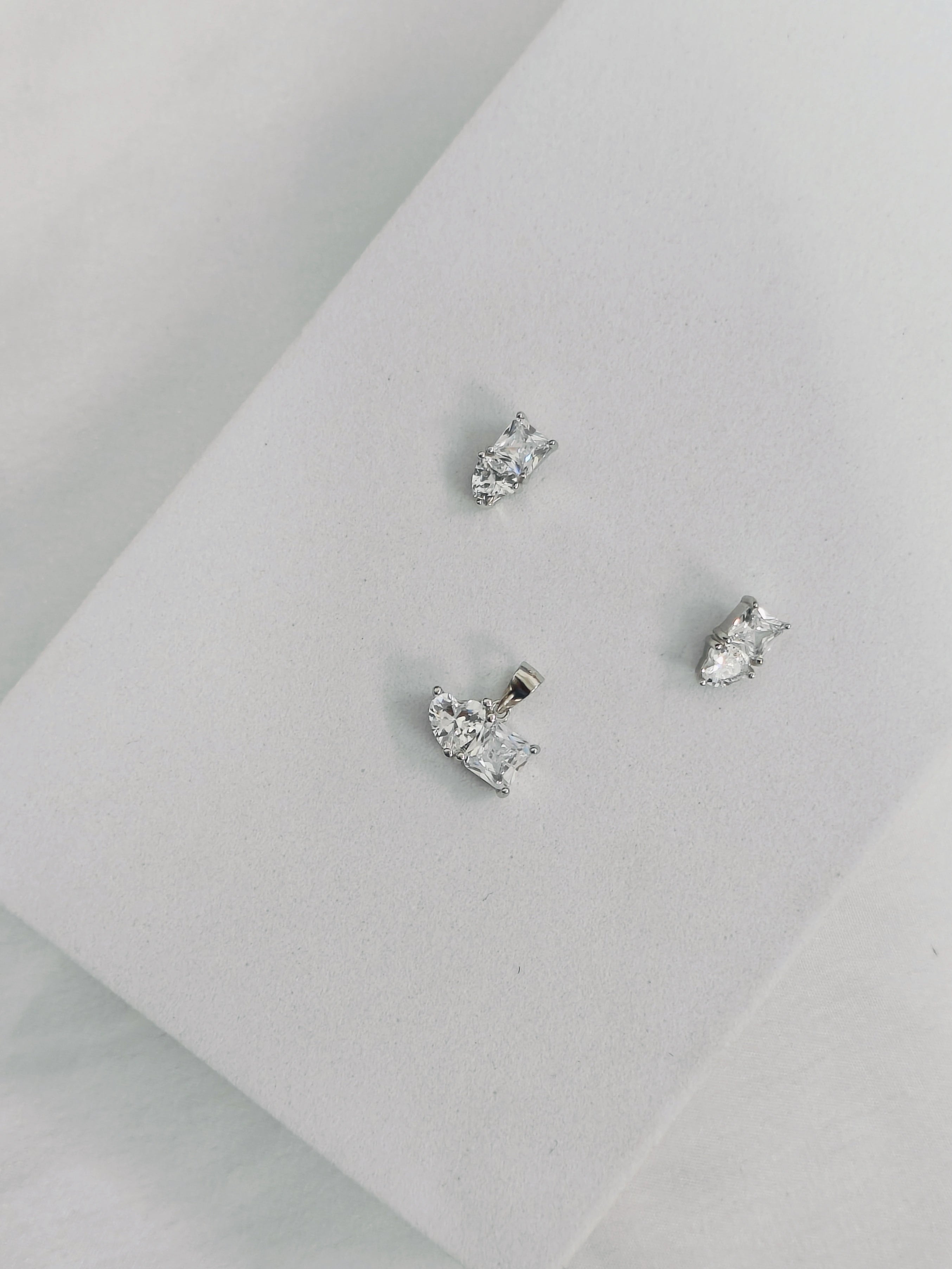 Three silver stud earrings on a light gray surface