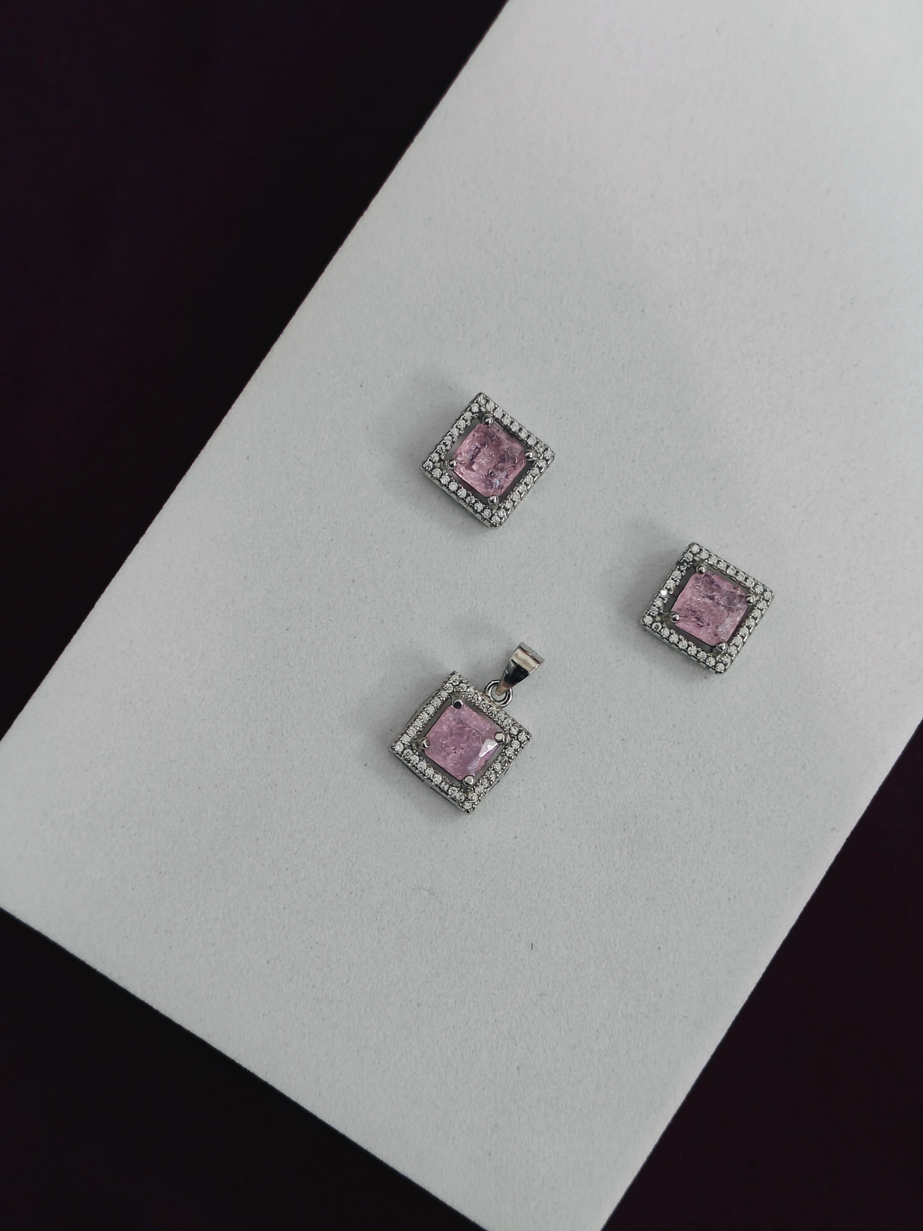 Jewelry set with pink gemstones and silver frames on a light gray background