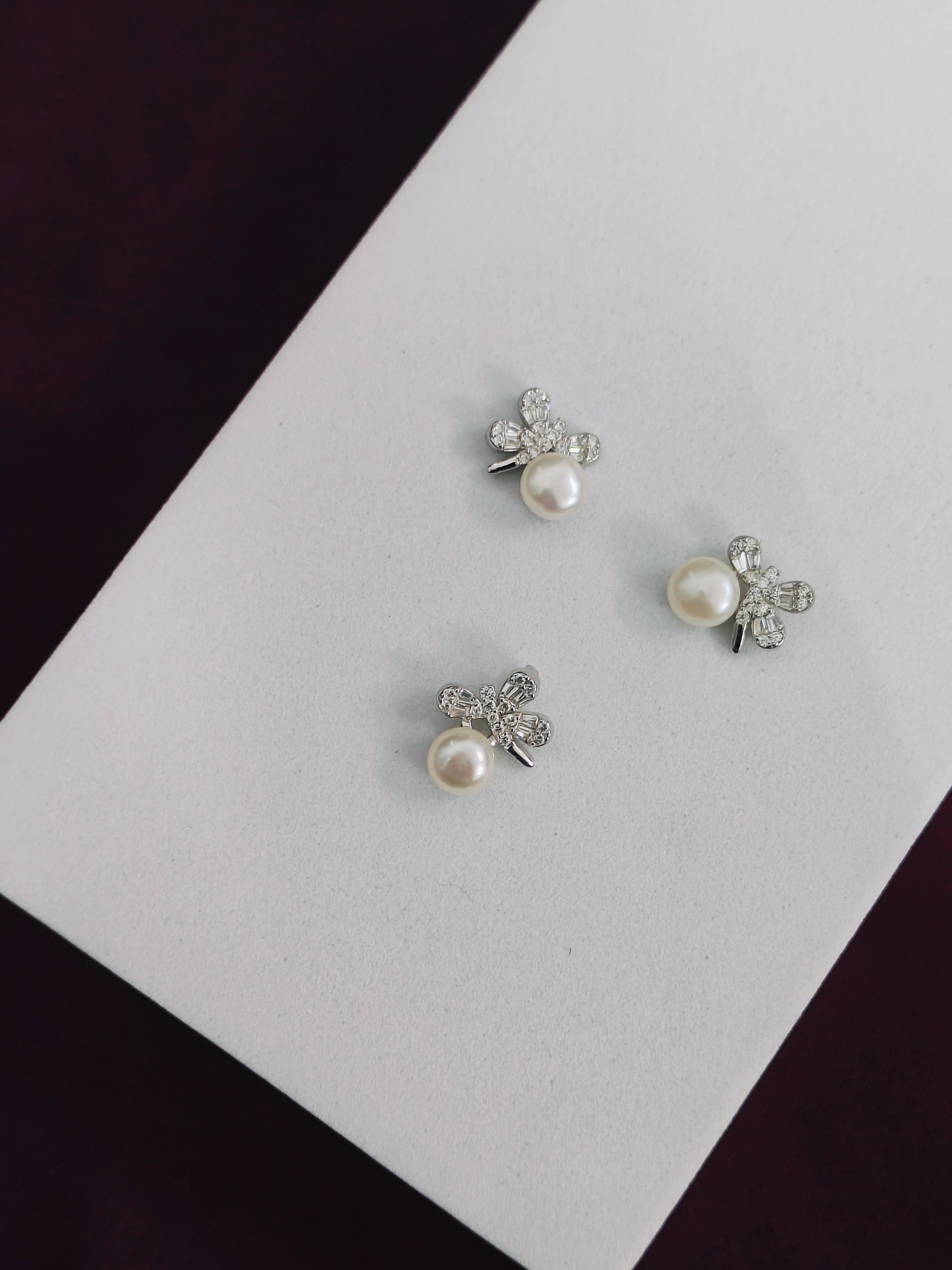 Pair of pearl and crystal earrings on a white card with a dark background