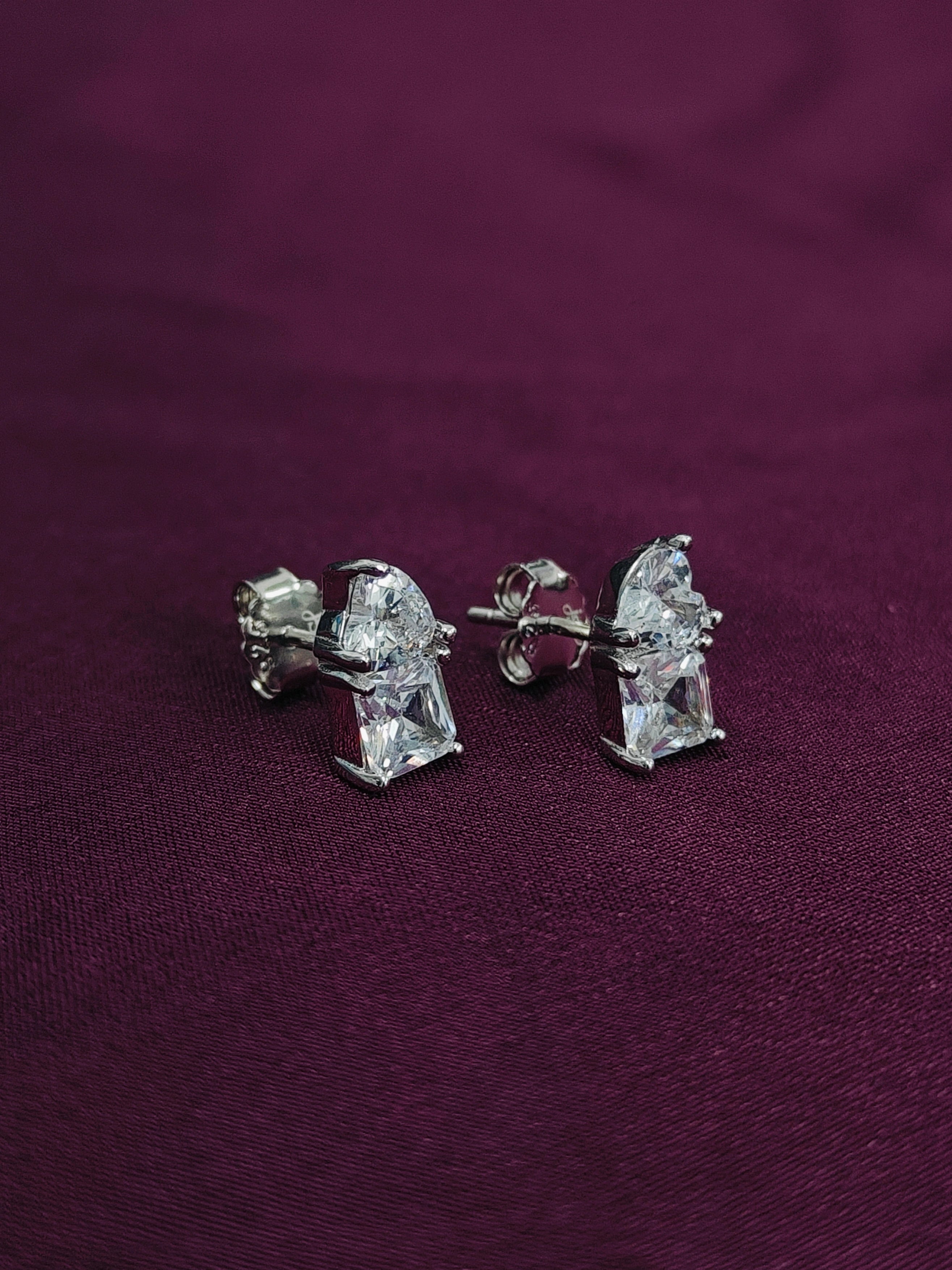 Diamond stud earrings on a purple fabric background