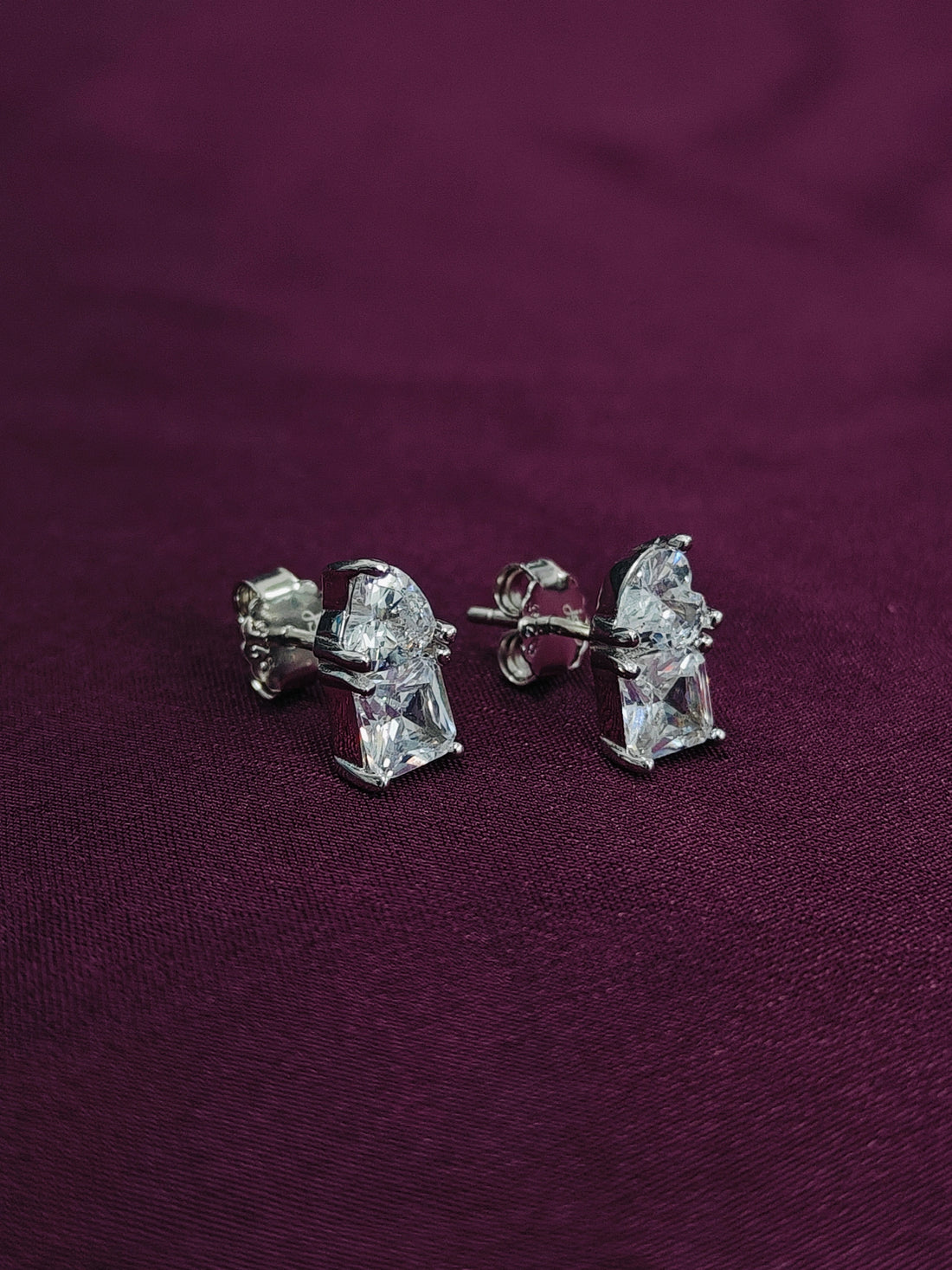 Diamond stud earrings on a purple fabric background