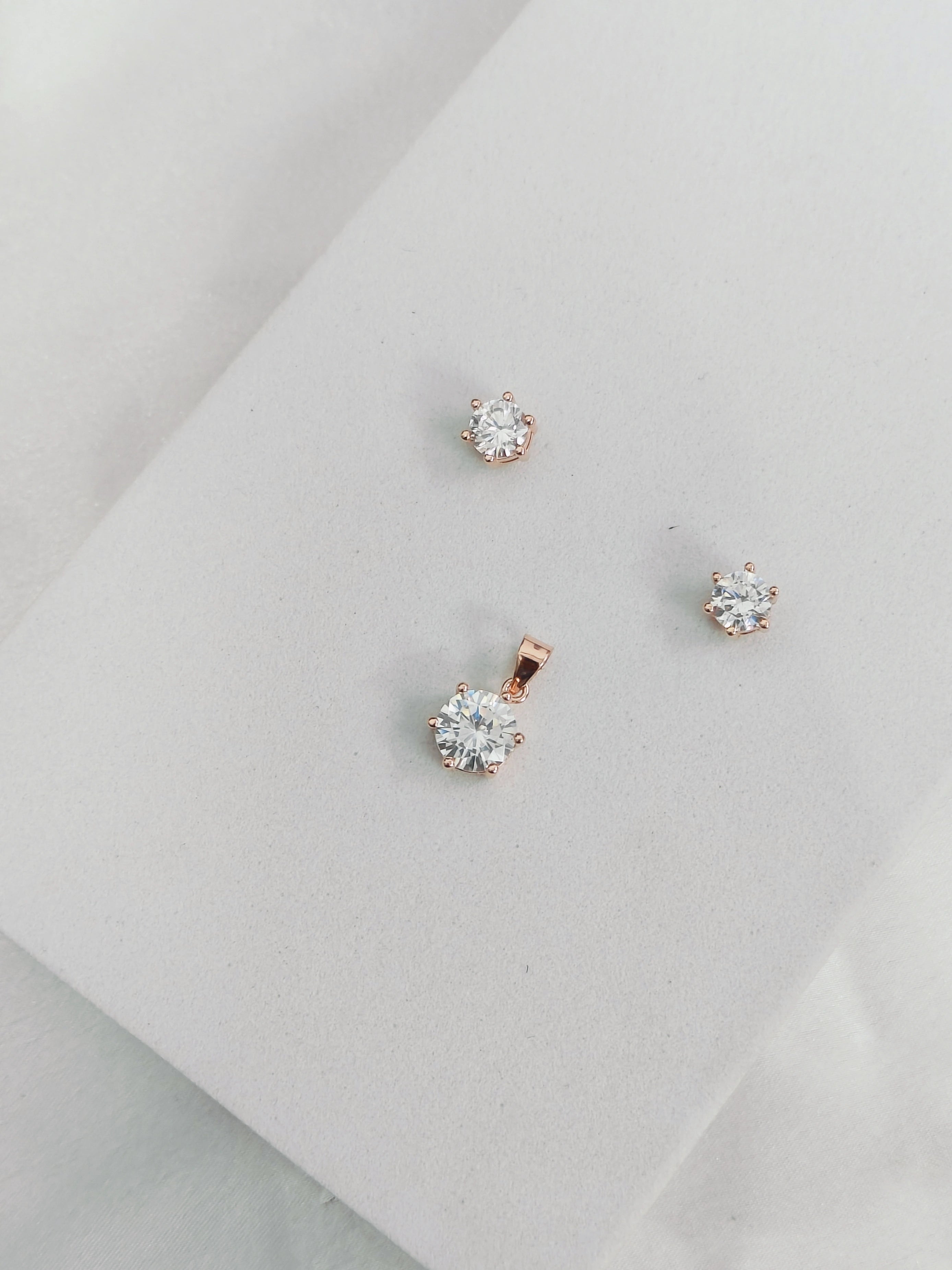 Rose gold stud earrings on a light gray surface