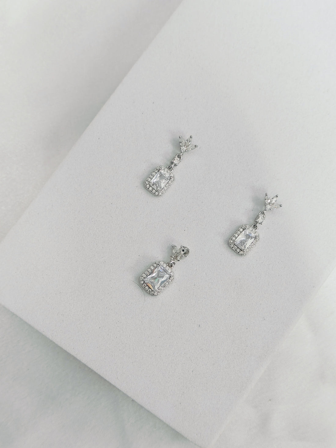 Pair of silver earrings with gemstones on a light gray background