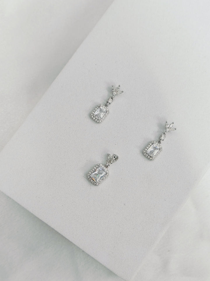 Pair of silver earrings with gemstones on a light gray background