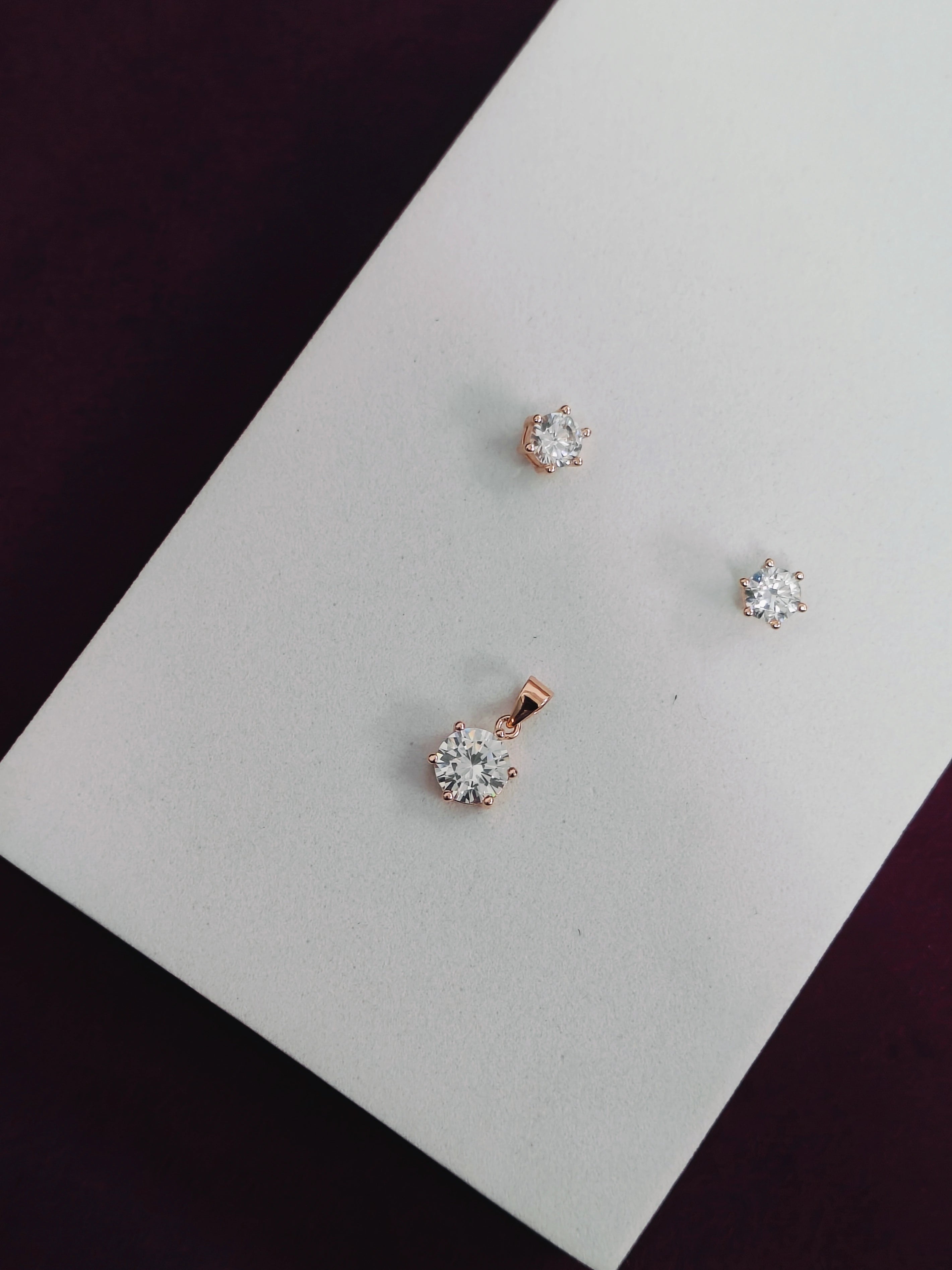 Rose gold and silver stud earrings on a white card with a dark background