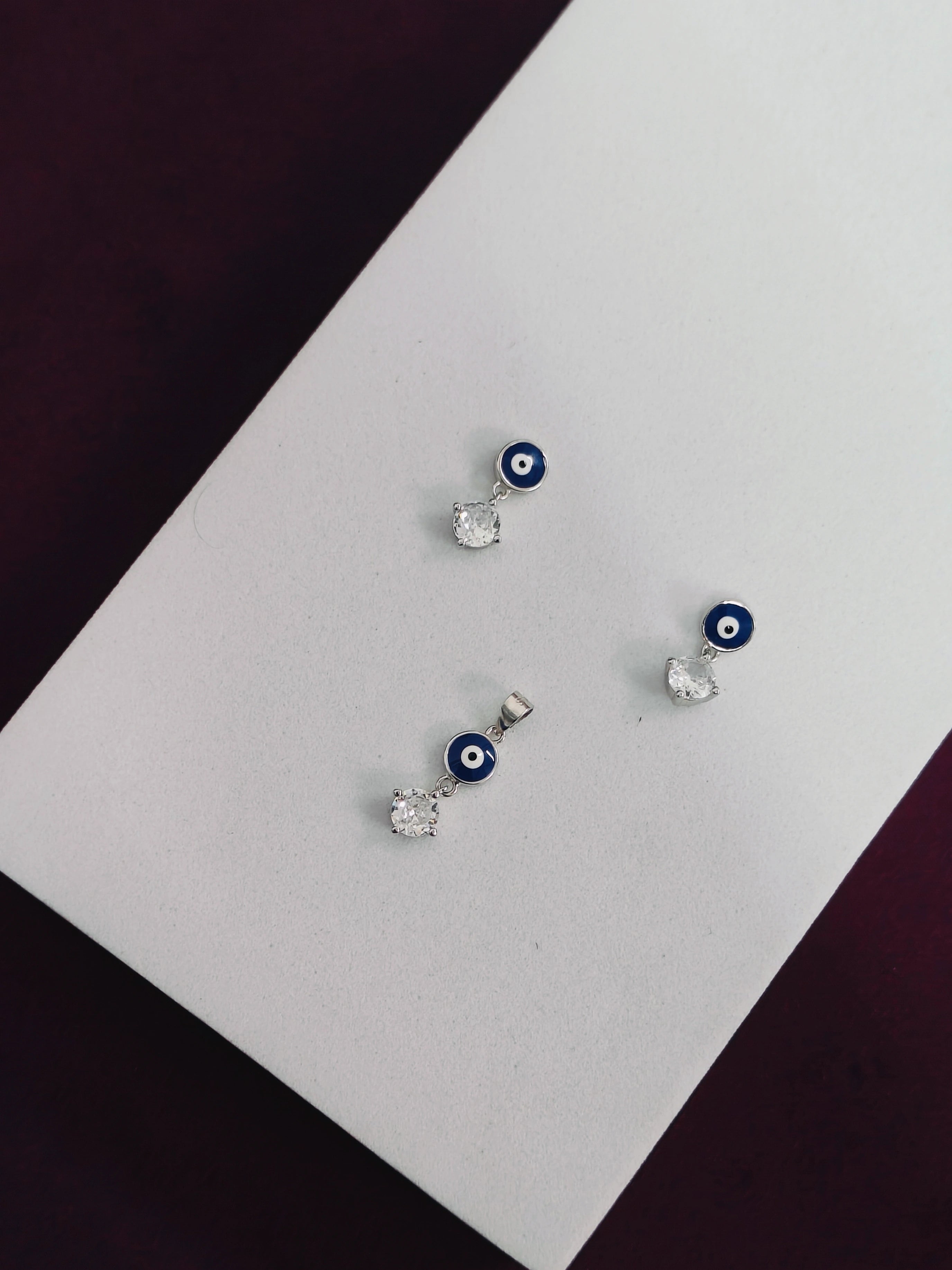 Pair of earrings with blue evil eye design on a white card