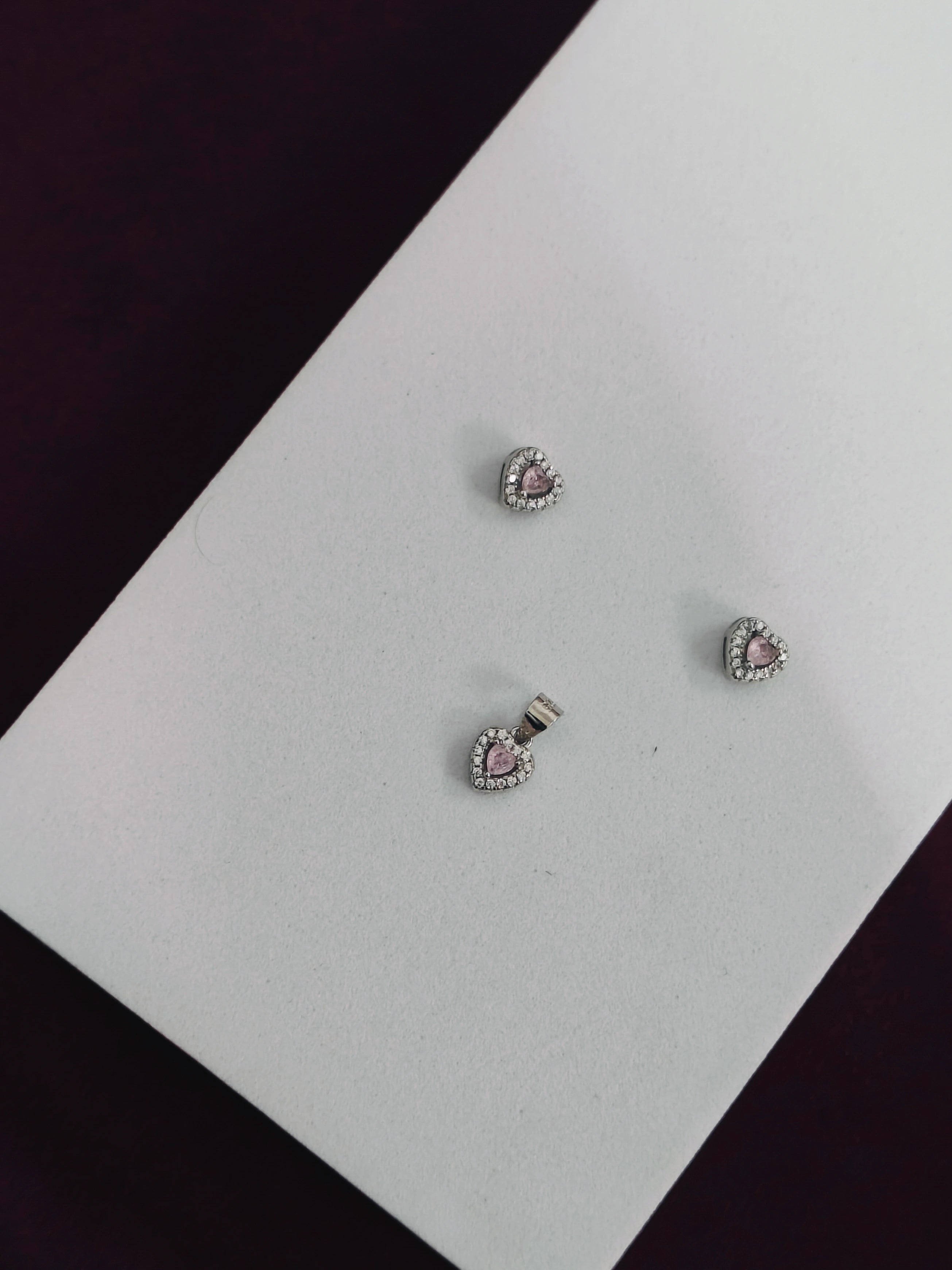 Heart-shaped earrings with pink stones on a white card