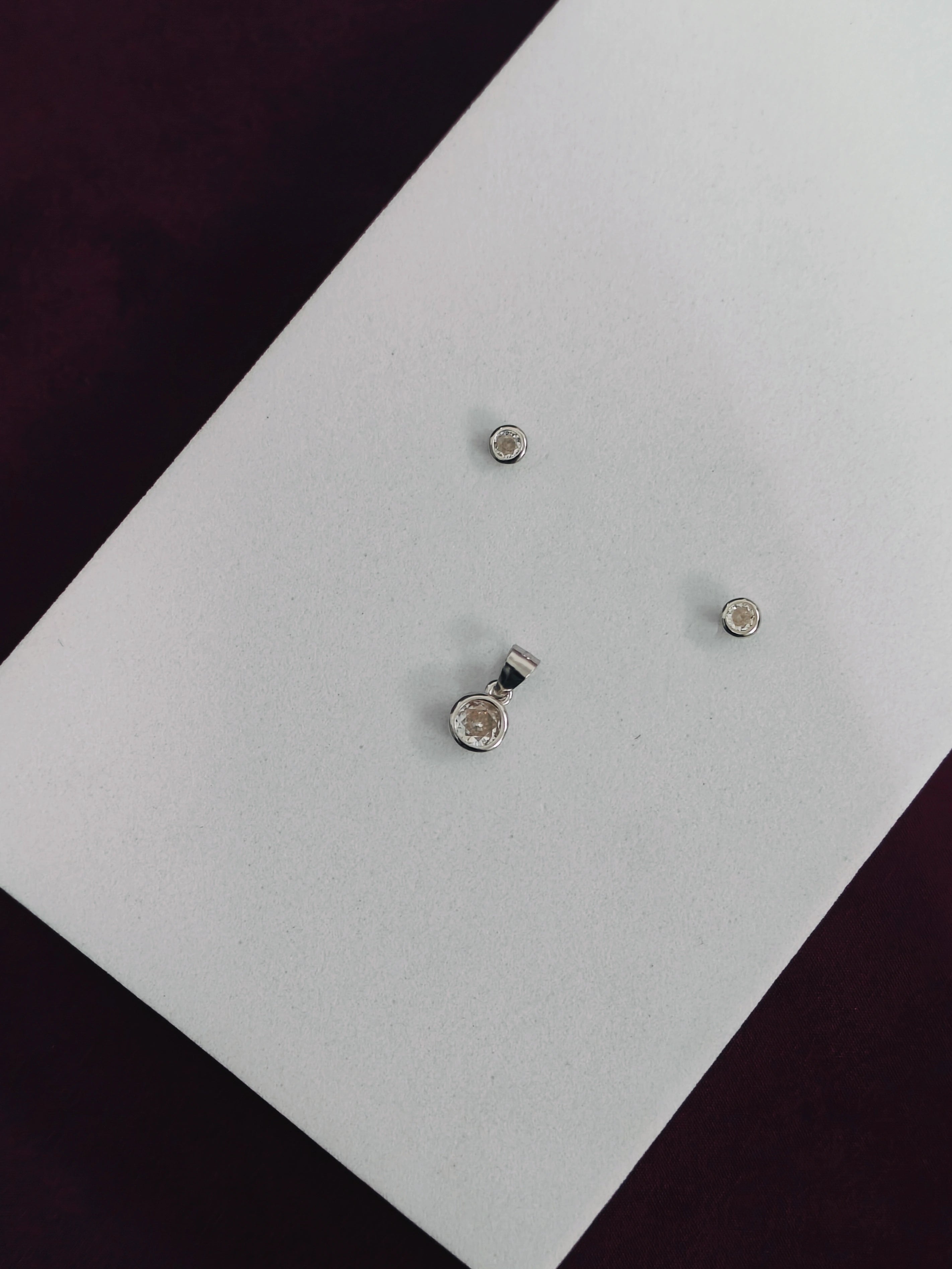 Three silver earrings on a white card with a black background