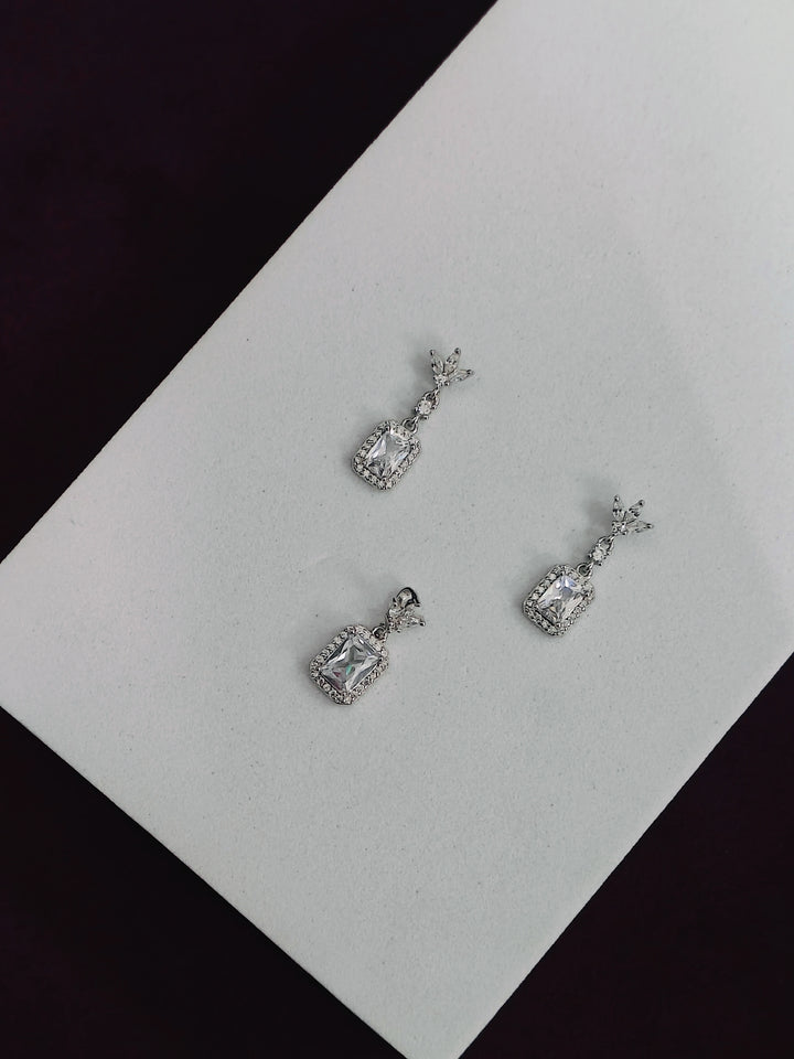 Pair of silver earrings on a white card with a black background