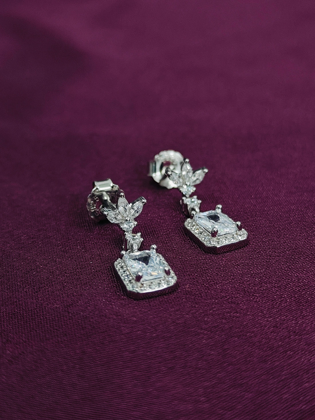 Silver earrings with gemstones on a purple fabric background