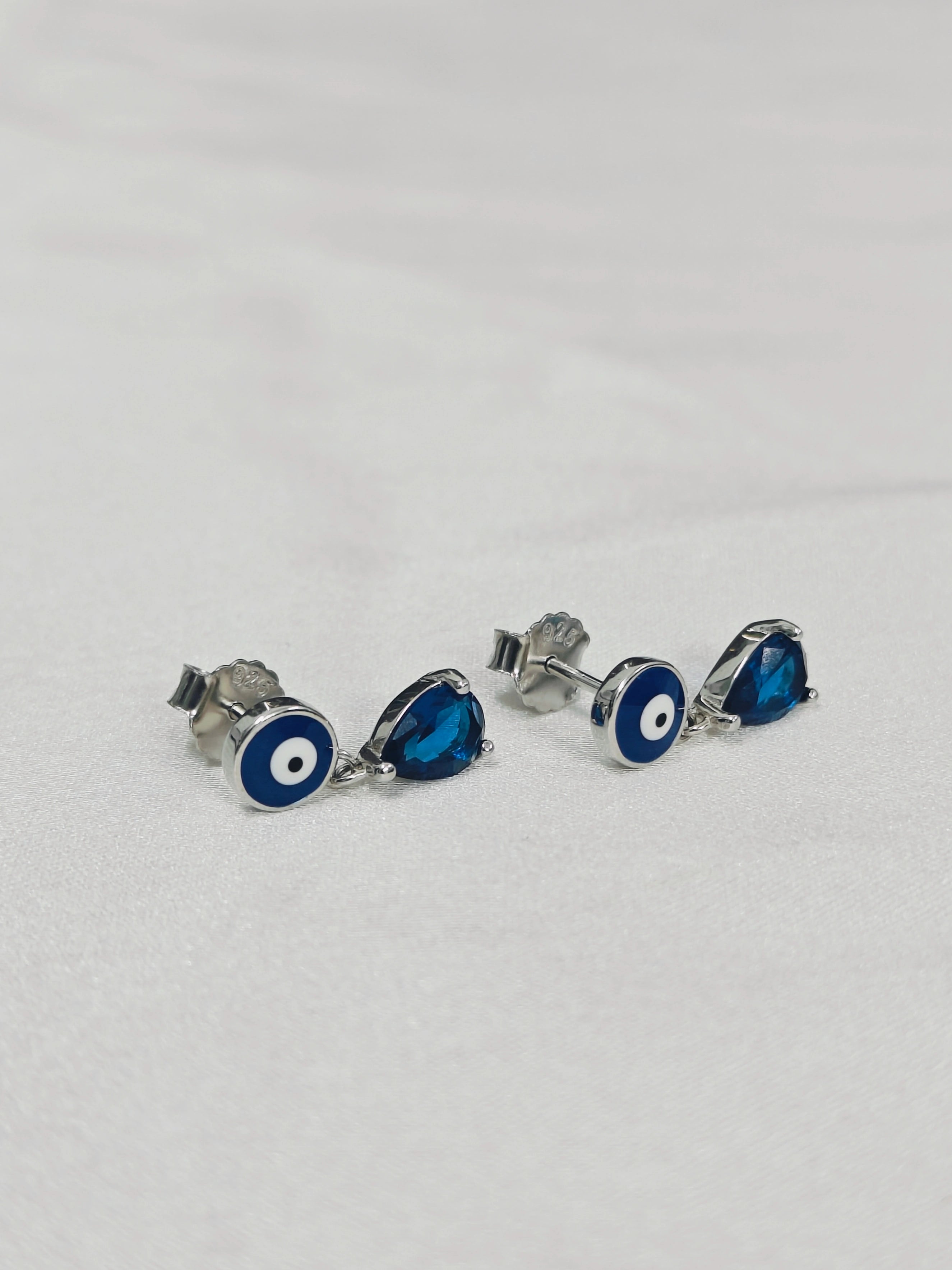 Silver earrings with blue circular stones on a light gray background