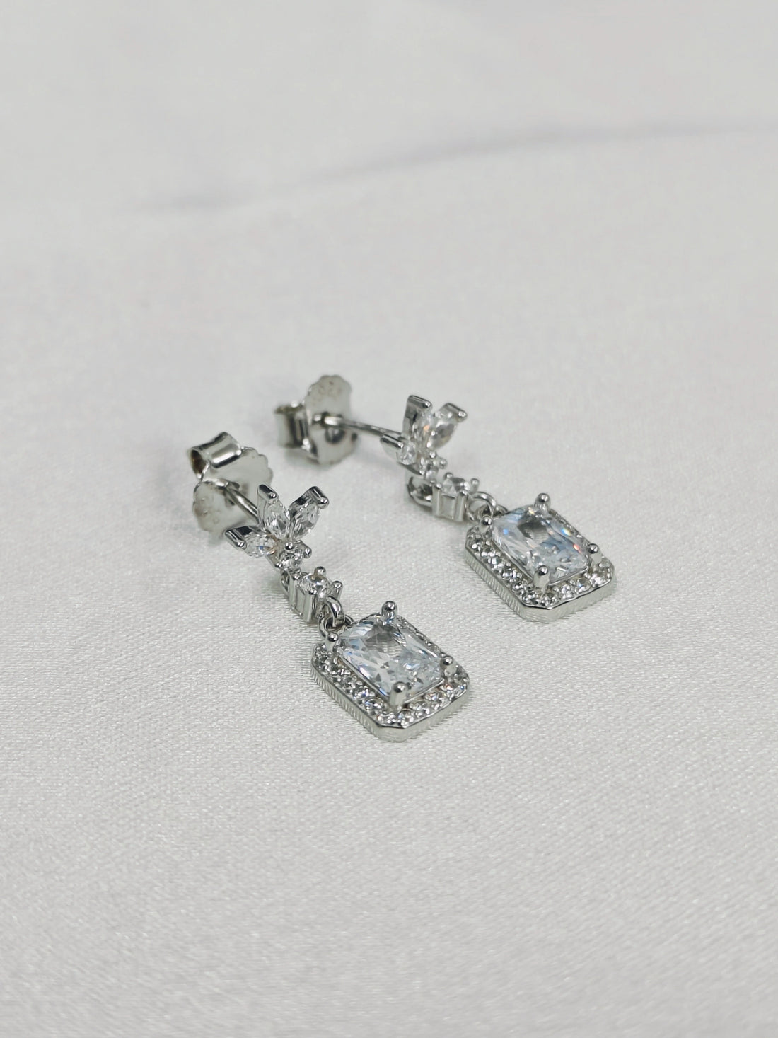 Silver earrings with gemstones on a light gray background
