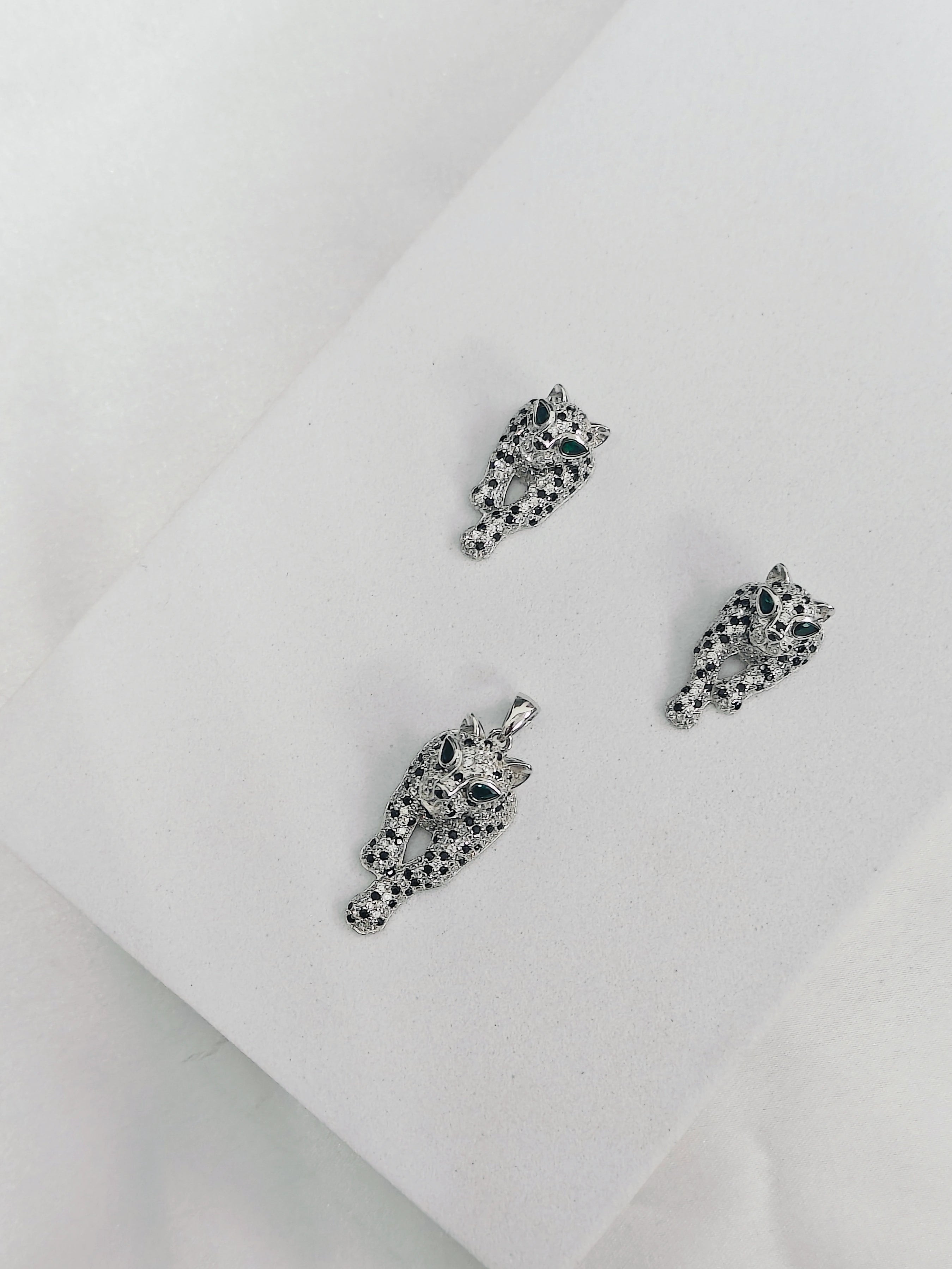 Pair of silver panther earrings with black gemstones on a white background