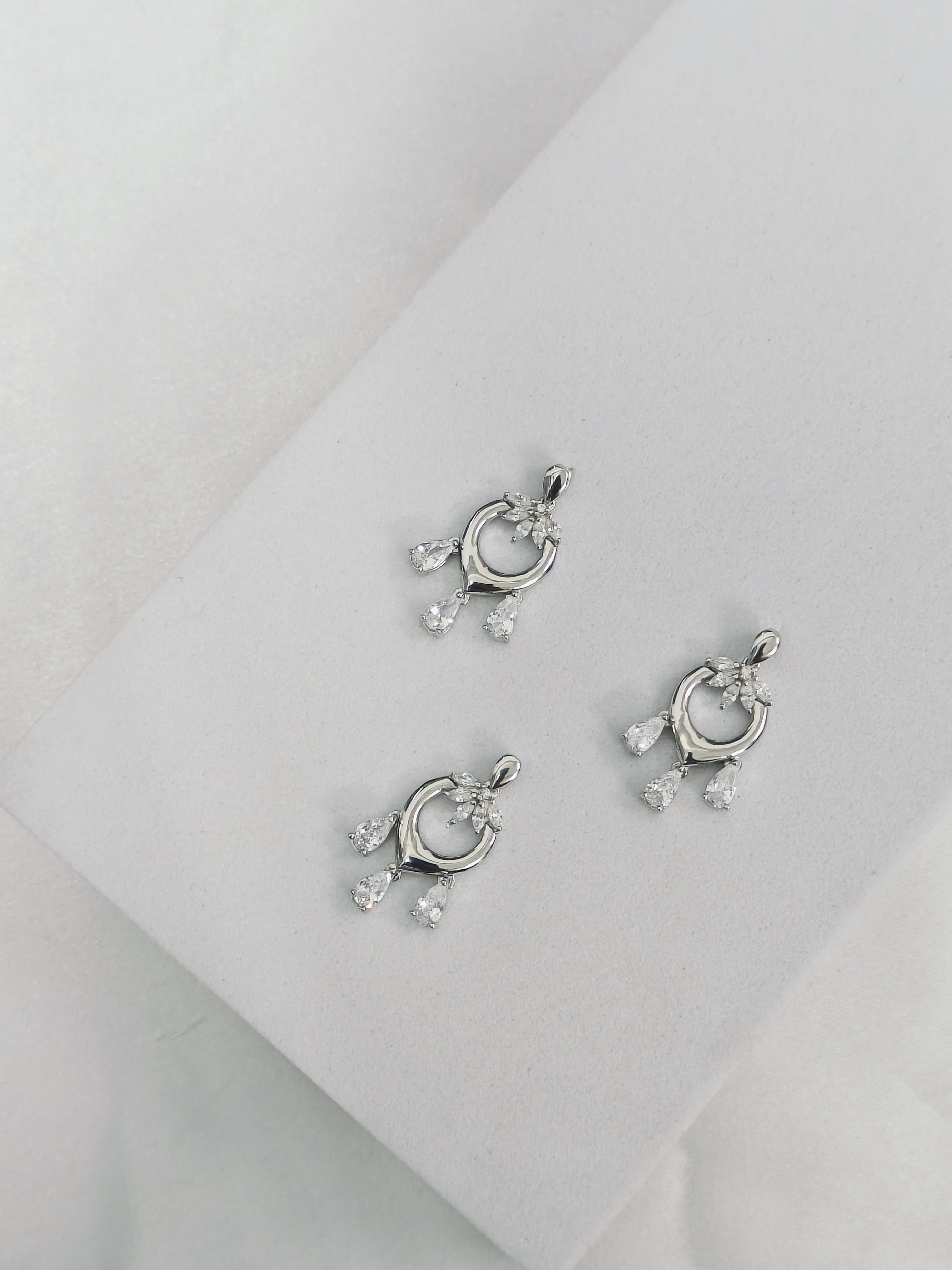 Pair of silver earrings with small gemstones on a light gray background