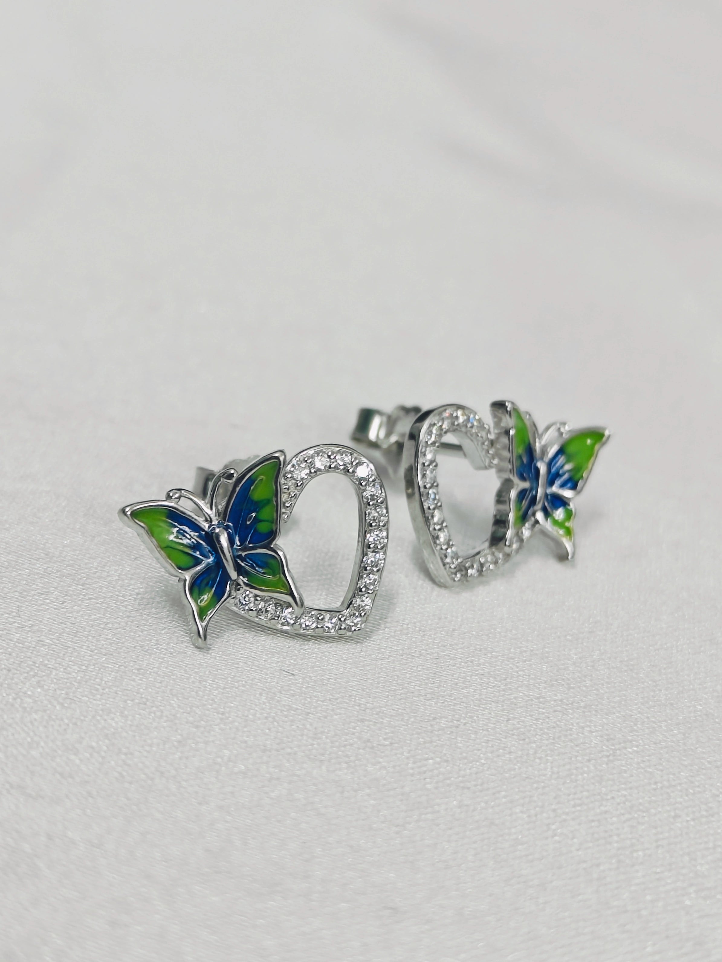 Butterfly-shaped earrings with blue and green details on a light gray background