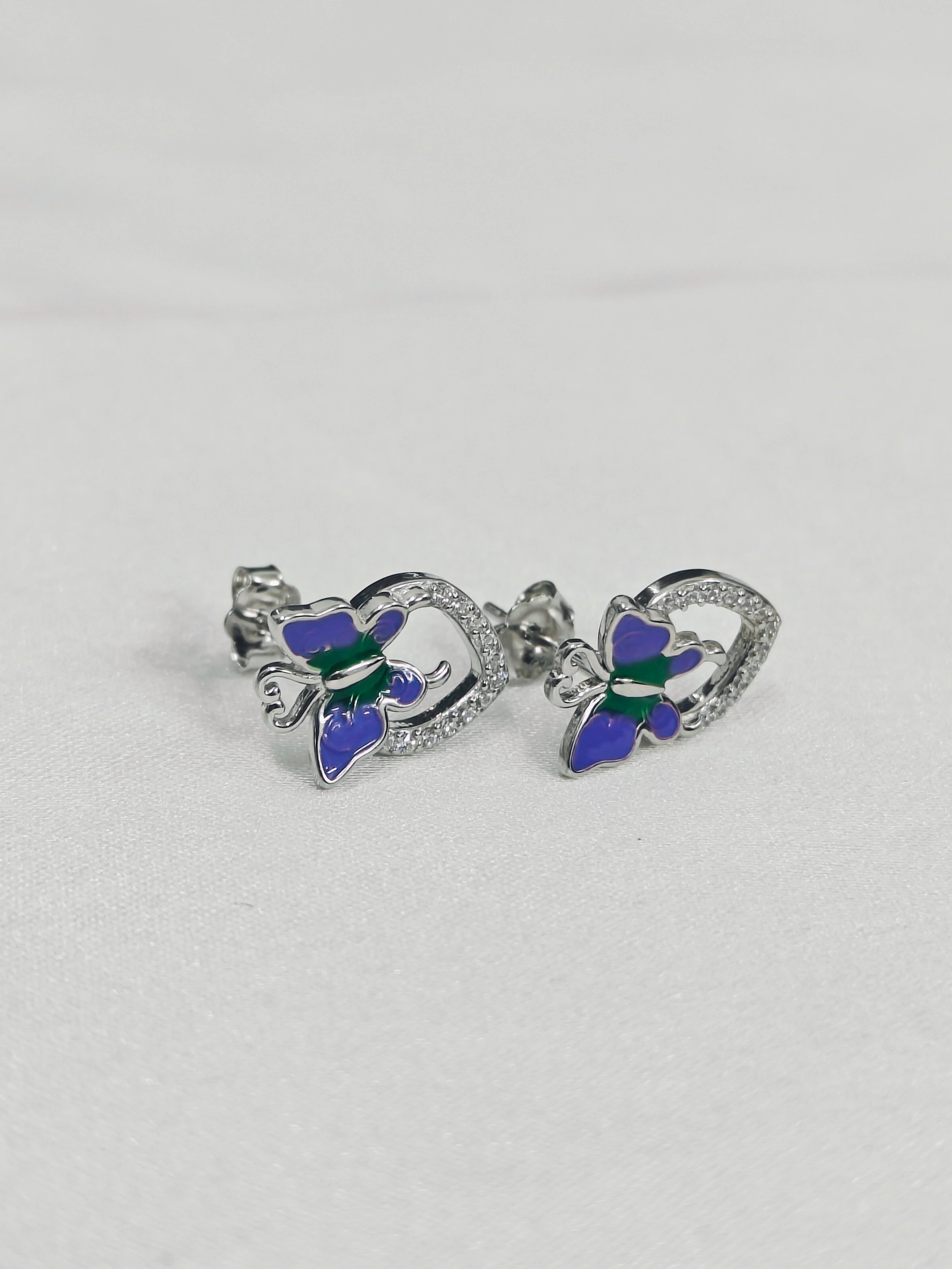 Butterfly-shaped earrings with blue and green details on a light gray background
